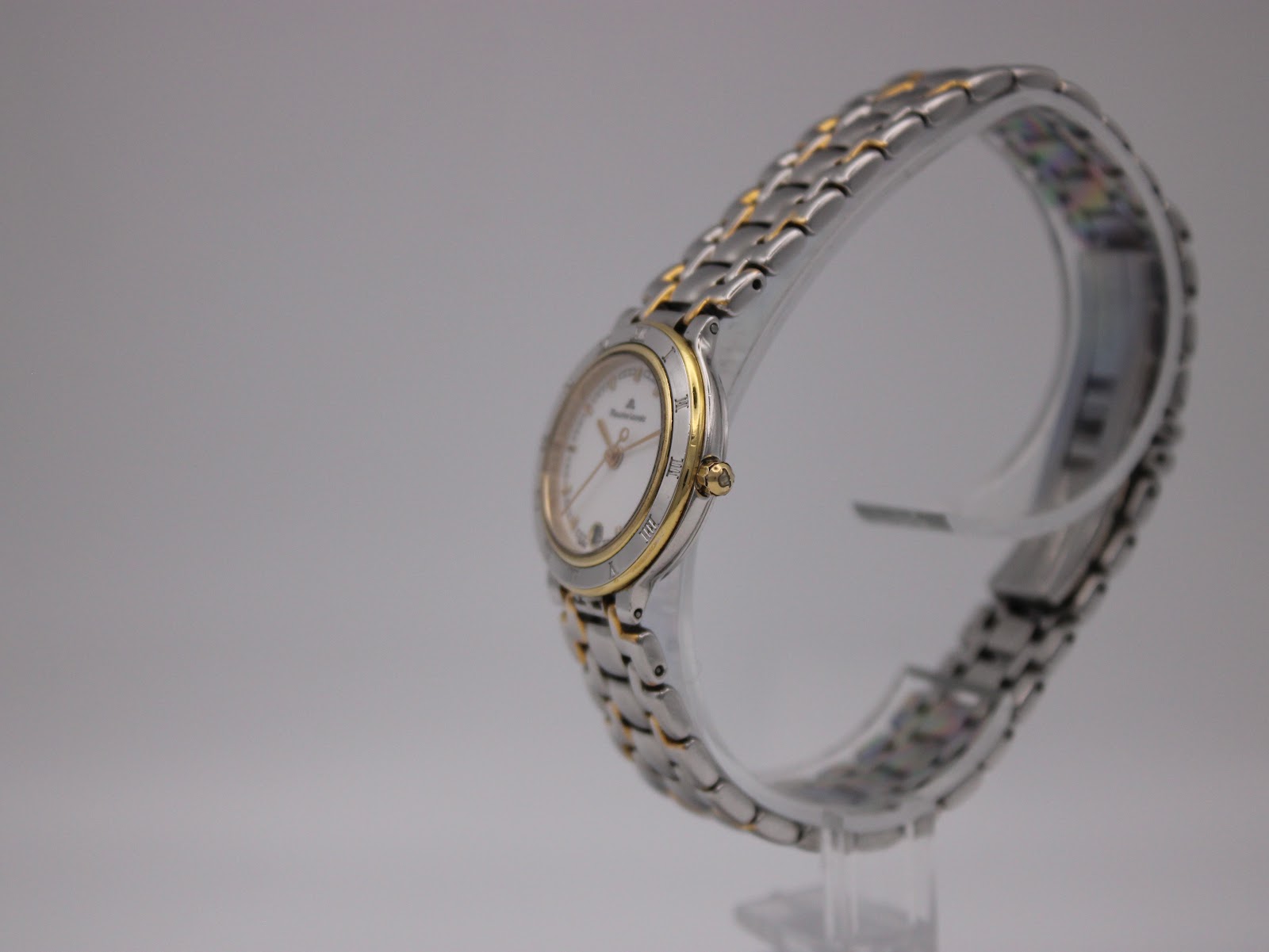 Angled side view of the Maurice Lacroix watch showing the gold-plated crown and two-tone bracelet.