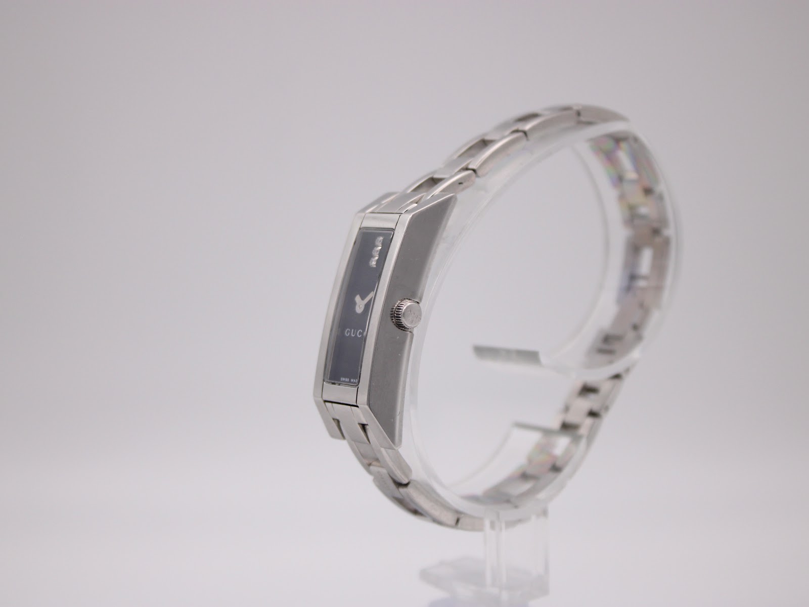 Side view of the Gucci 110 watch on a display stand, highlighting the slim profile and integrated bracelet design.