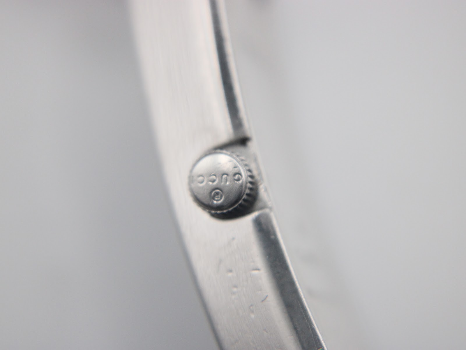 Macro shot of the Gucci-signed crown on the side of the watch case.