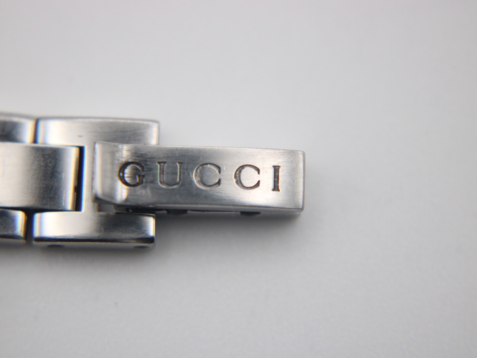 Close-up of the deployant clasp on the Gucci 110 bracelet, clearly showing the 'GUCCI' engraving.