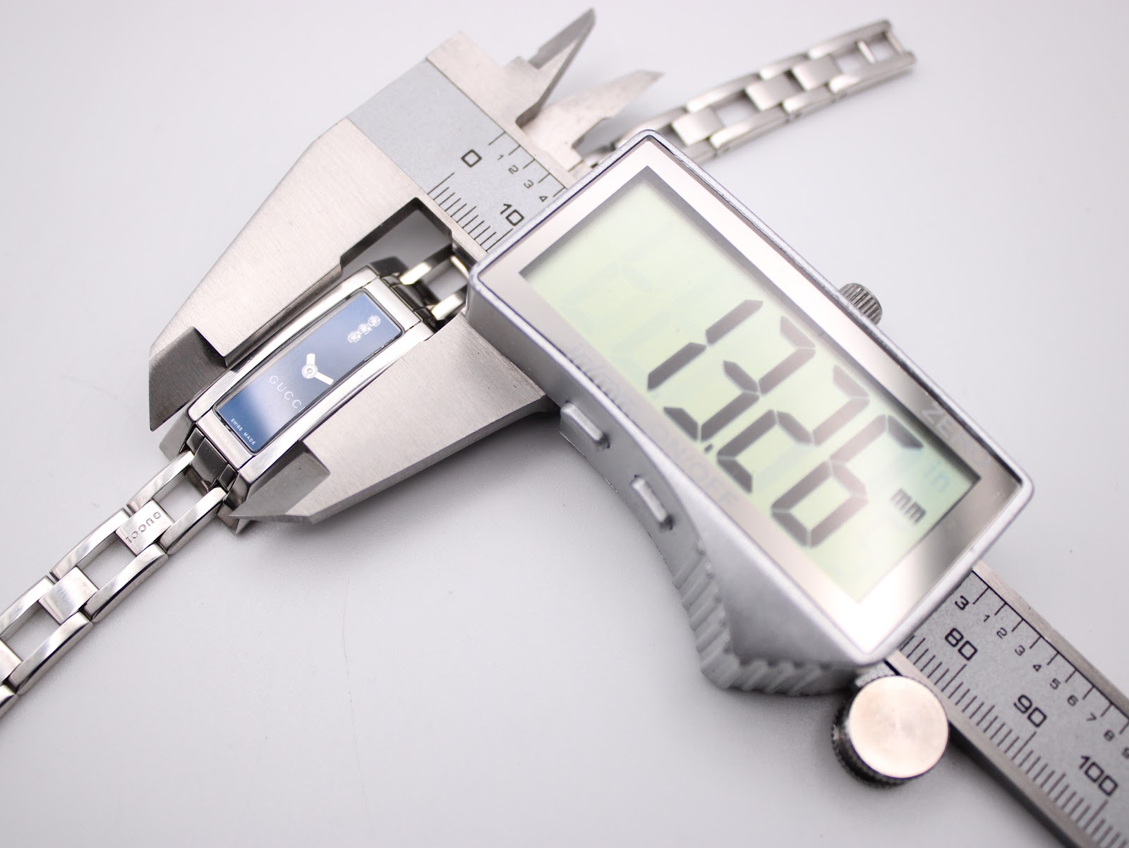 Digital caliper measuring the case width of the Gucci 110 watch, displaying 13.26mm.