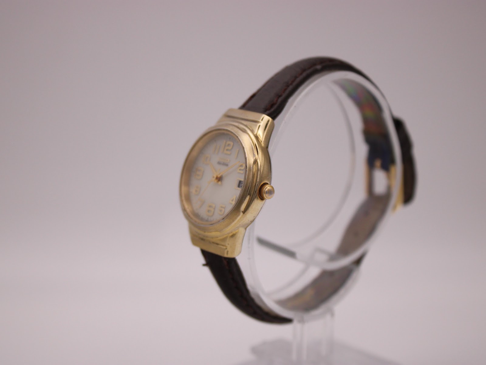 Angled side view of the Citizen Eco-Drive watch on a display stand, highlighting the gold-tone case and crown.
