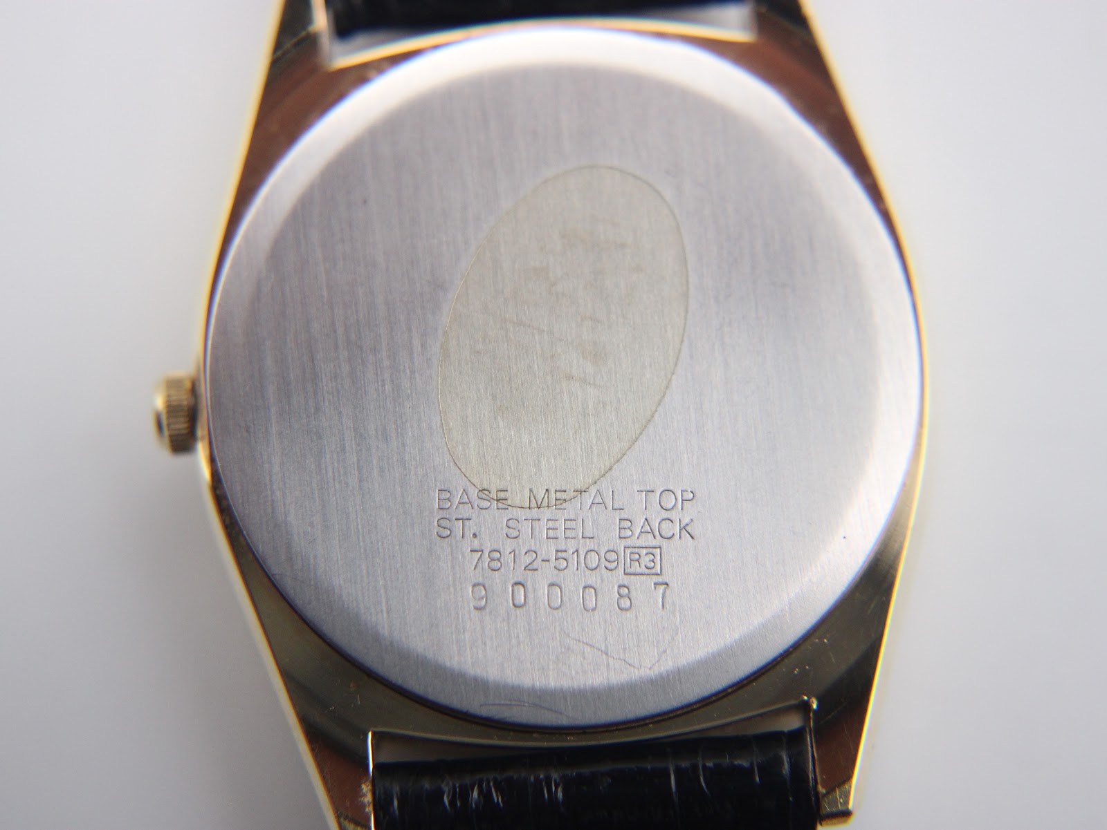 Close-up of the brushed stainless steel case back, showing the model number 7812-5109, serial number 900087, and material markings.