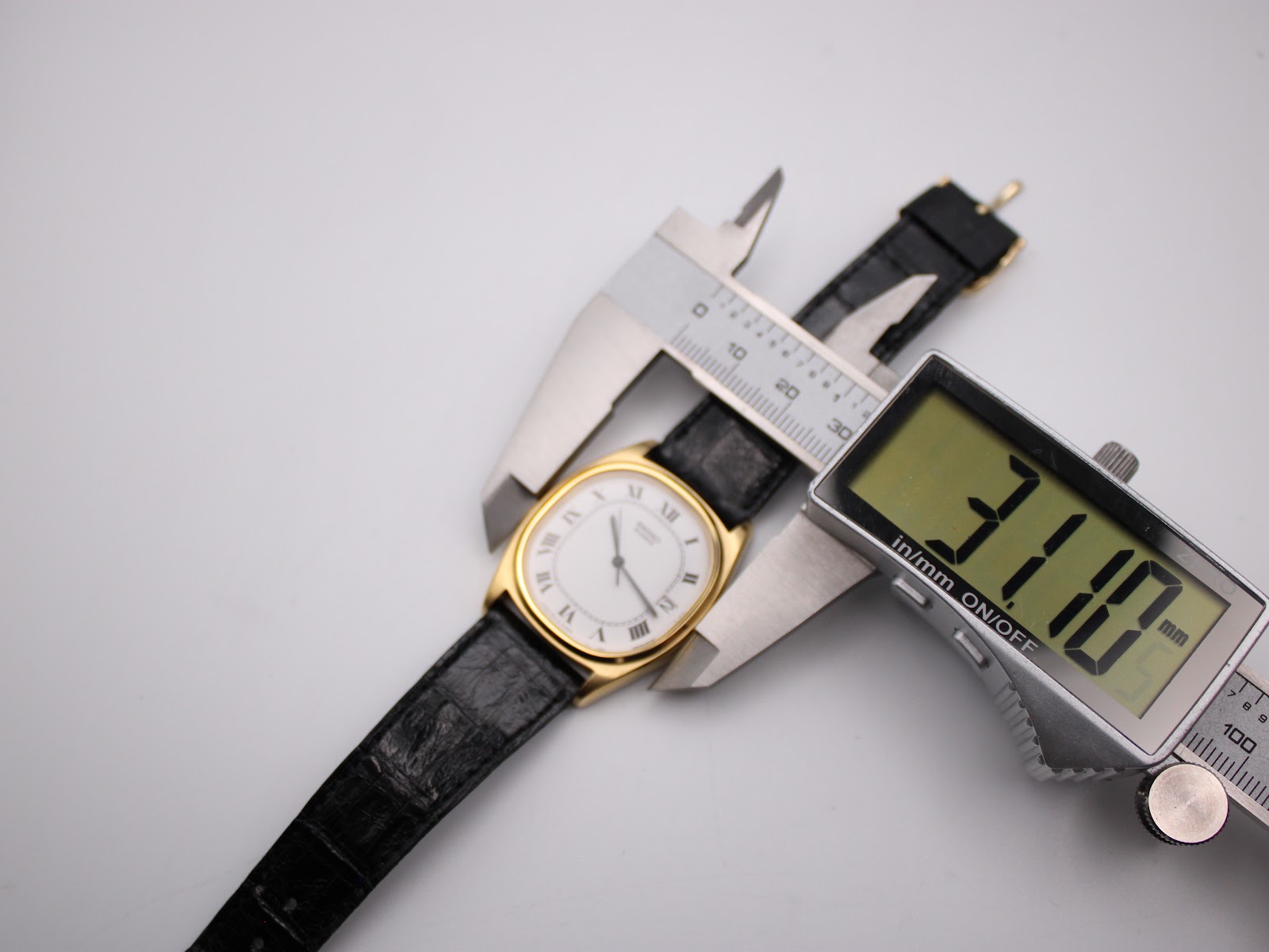 A digital caliper measuring the case width of the Seiko watch, displaying a precise measurement of 31.0 mm.