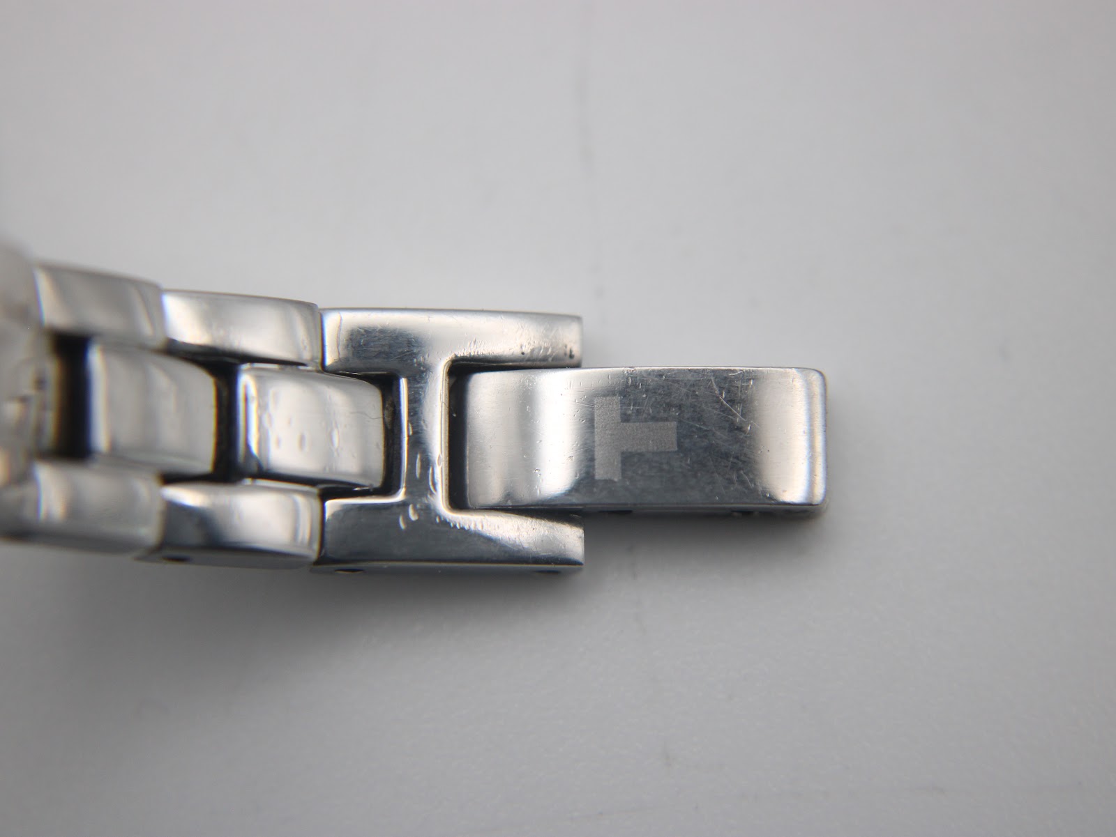 Close-up of the Tissot G345 bracelet clasp, displaying the Tissot 'T' logo and minor surface wear.