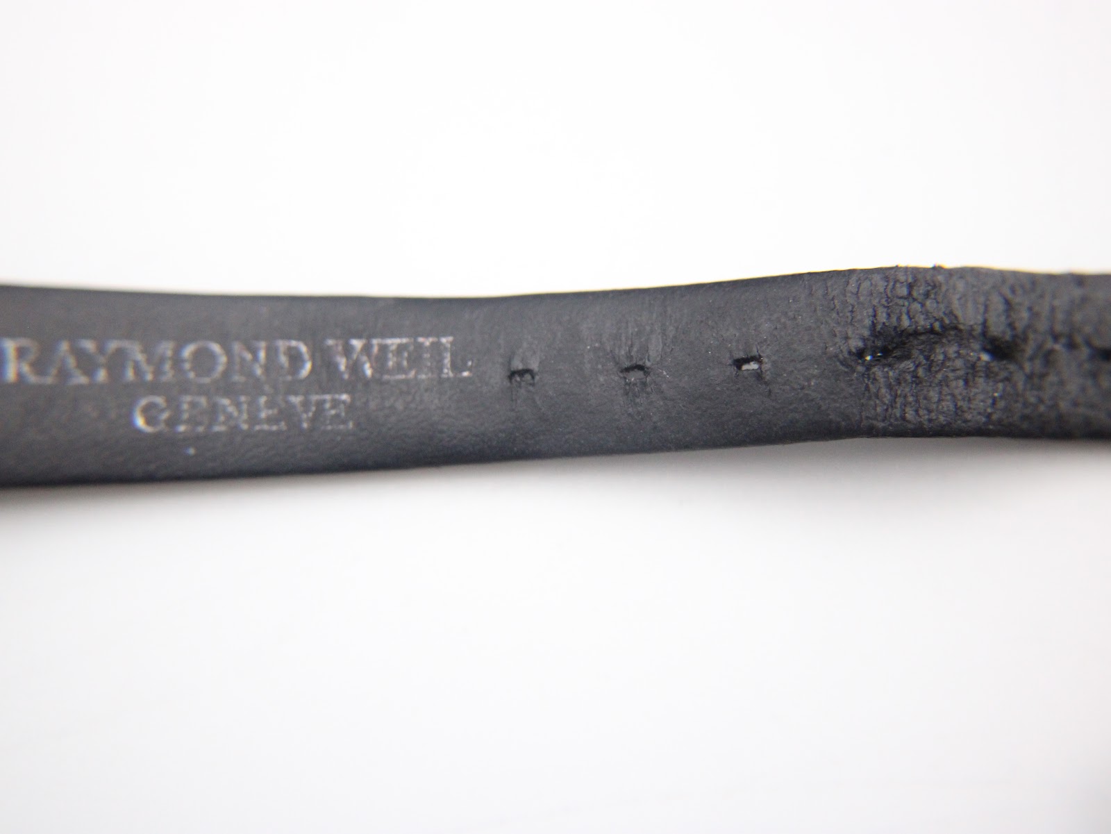 Close-up of the inner side of the black leather strap showing 'RAYMOND WEIL GENEVE' embossing.