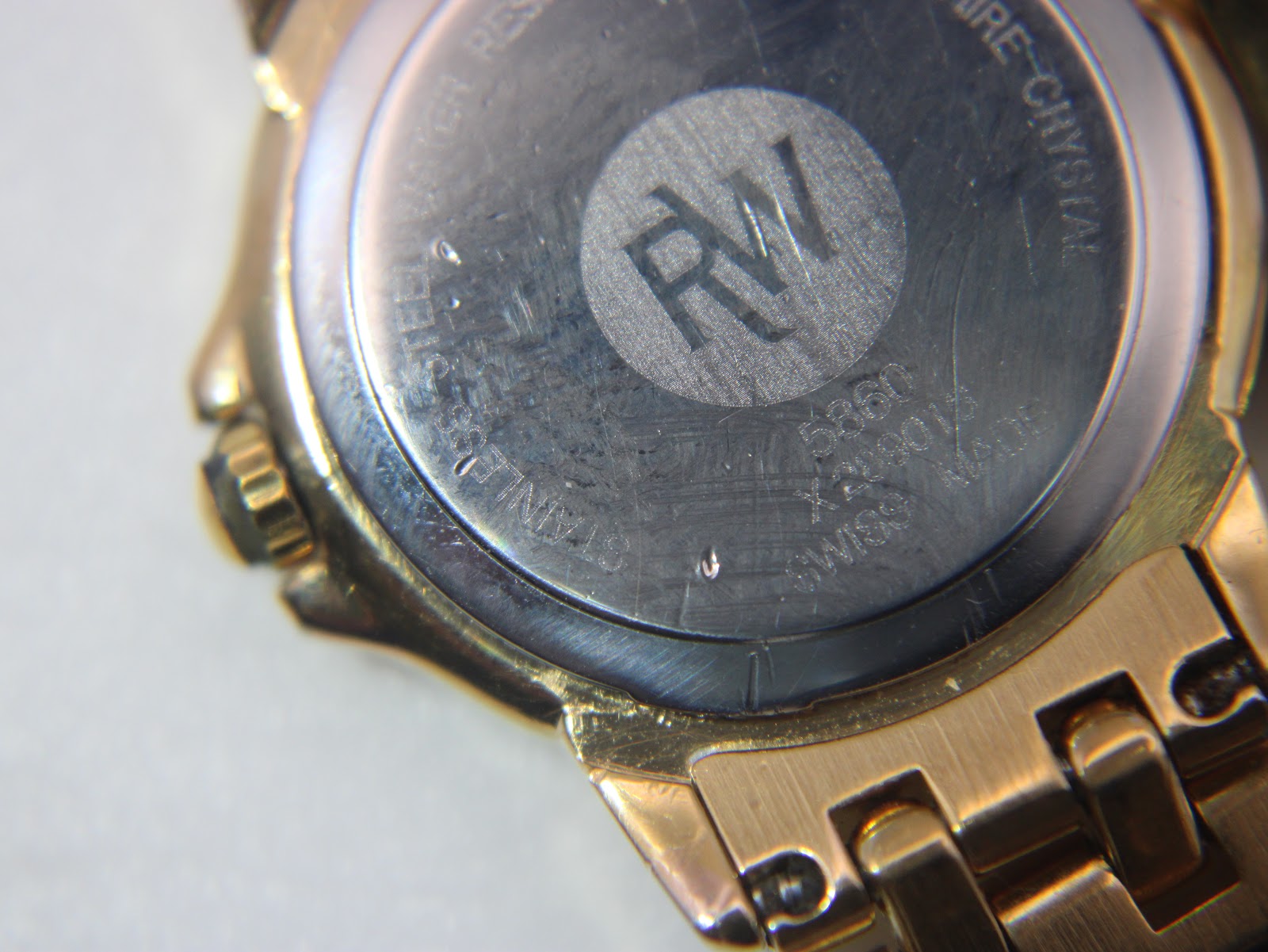 Close-up of the watch case back, showing 'RAYMOND WEIL', 'GENEVE', 'STAINLESS STEEL BACK', 'WATER RESISTANT', 'SAPPHIRE CRYSTAL', '5360', and serial number X238012.