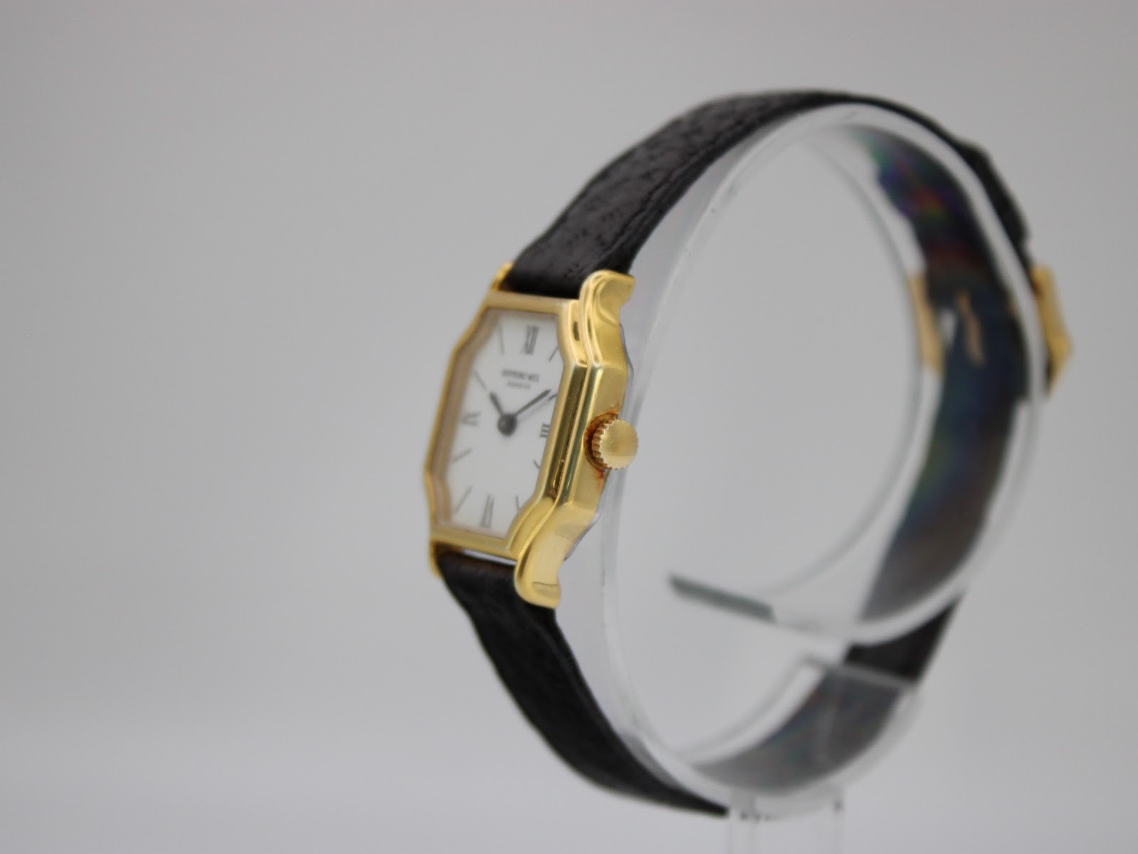 Angled side view of the Raymond Weil 737 watch on a display stand, highlighting the case profile and crown.
