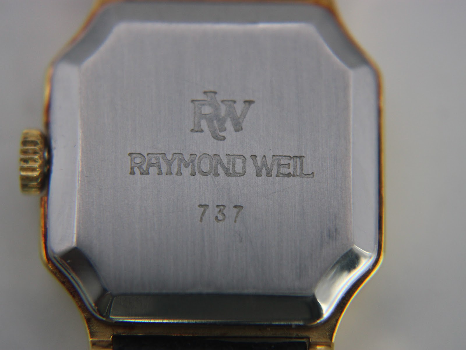 Close-up of the watch case back, engraved with 'RW', 'RAYMOND WEIL', and model number '737'.