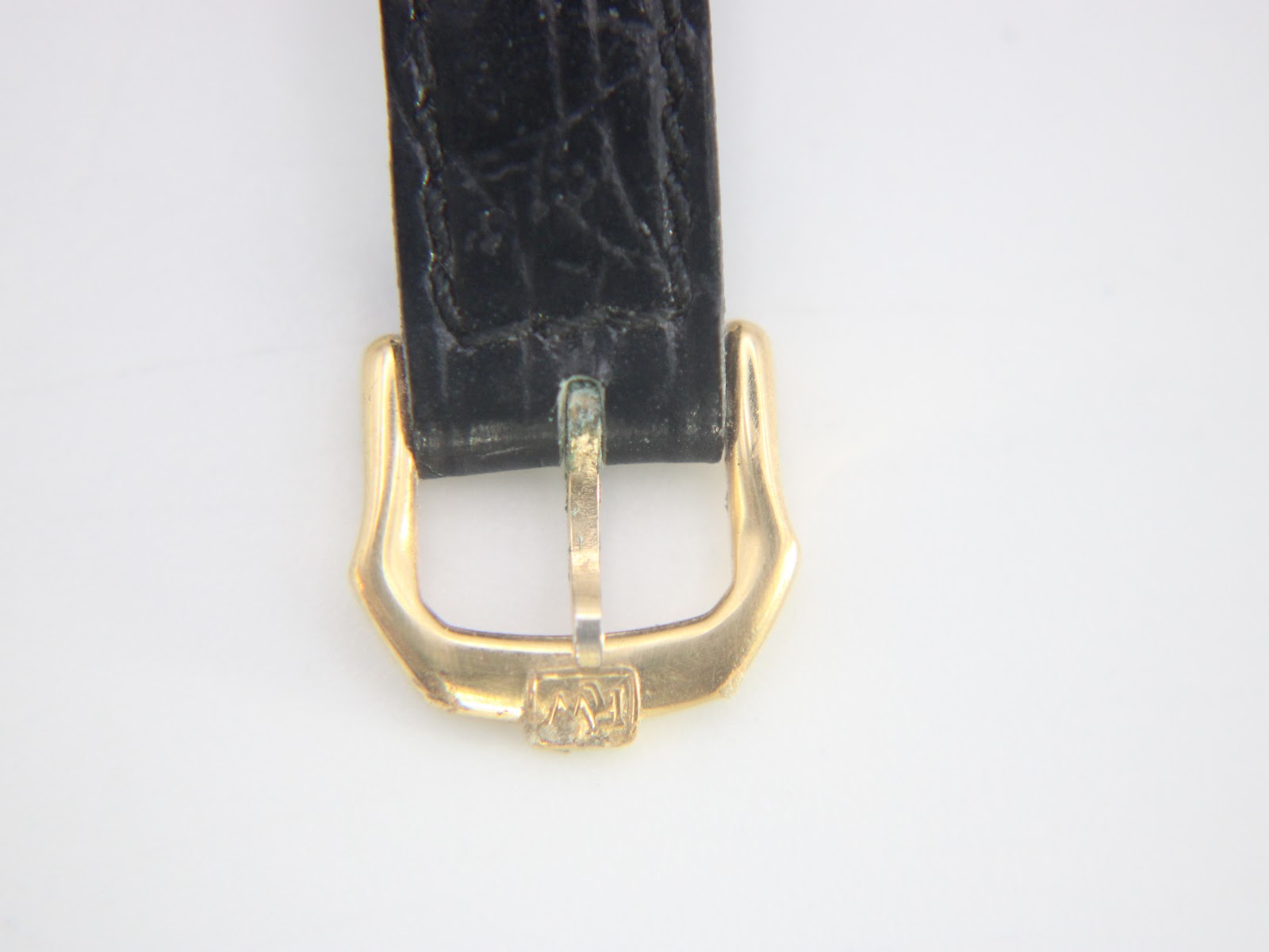 Close-up of the gold-tone buckle and the black leather strap's keeper, which features an embossed 'RW' logo.
