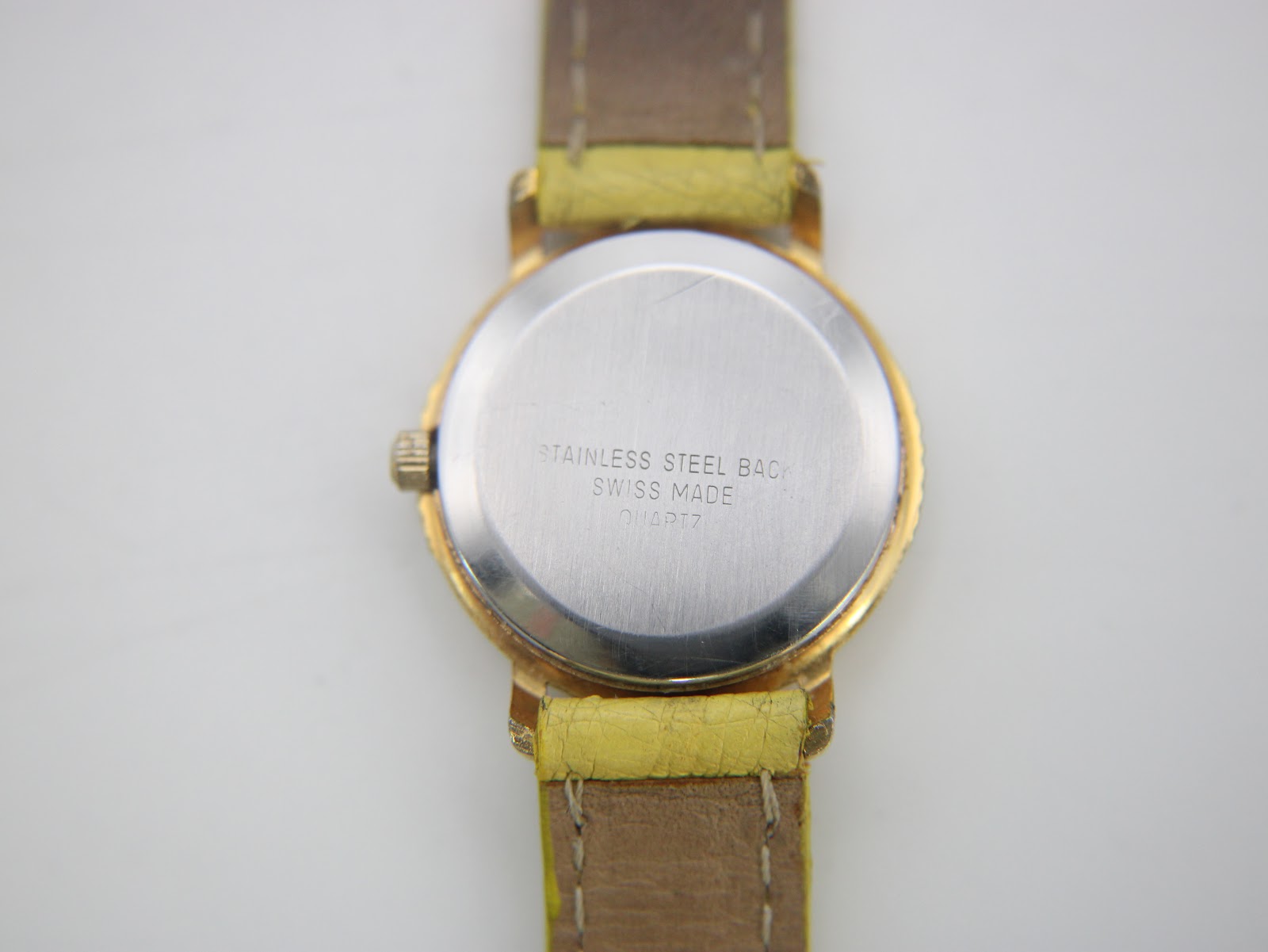 Close-up of the stainless steel case back of the René Gérard watch, showing "STAINLESS STEEL BACK", "SWISS MADE", and "QUARTZ" engravings.