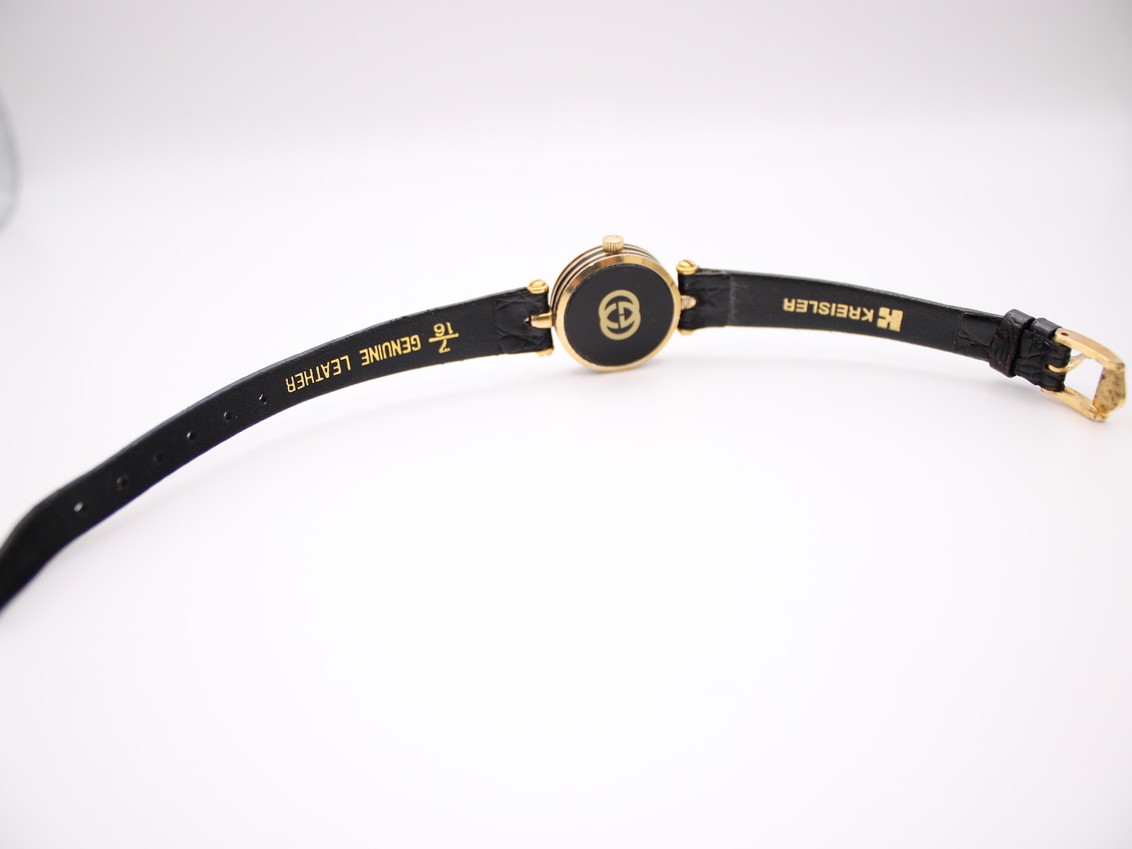 View of the watch from the back, showing the case back, the gold-tone signed buckle, and the black 'KREISLER' genuine leather strap.