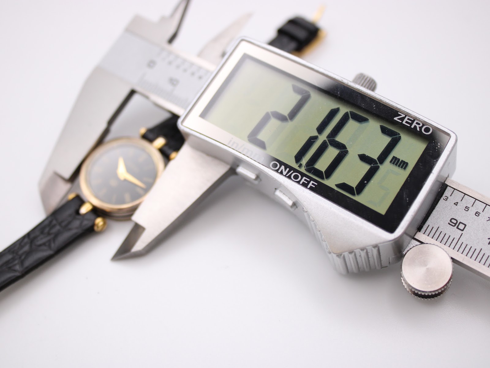 Close-up photo of a digital caliper measuring the watch case diameter, displaying an exact measurement of 21.63mm.