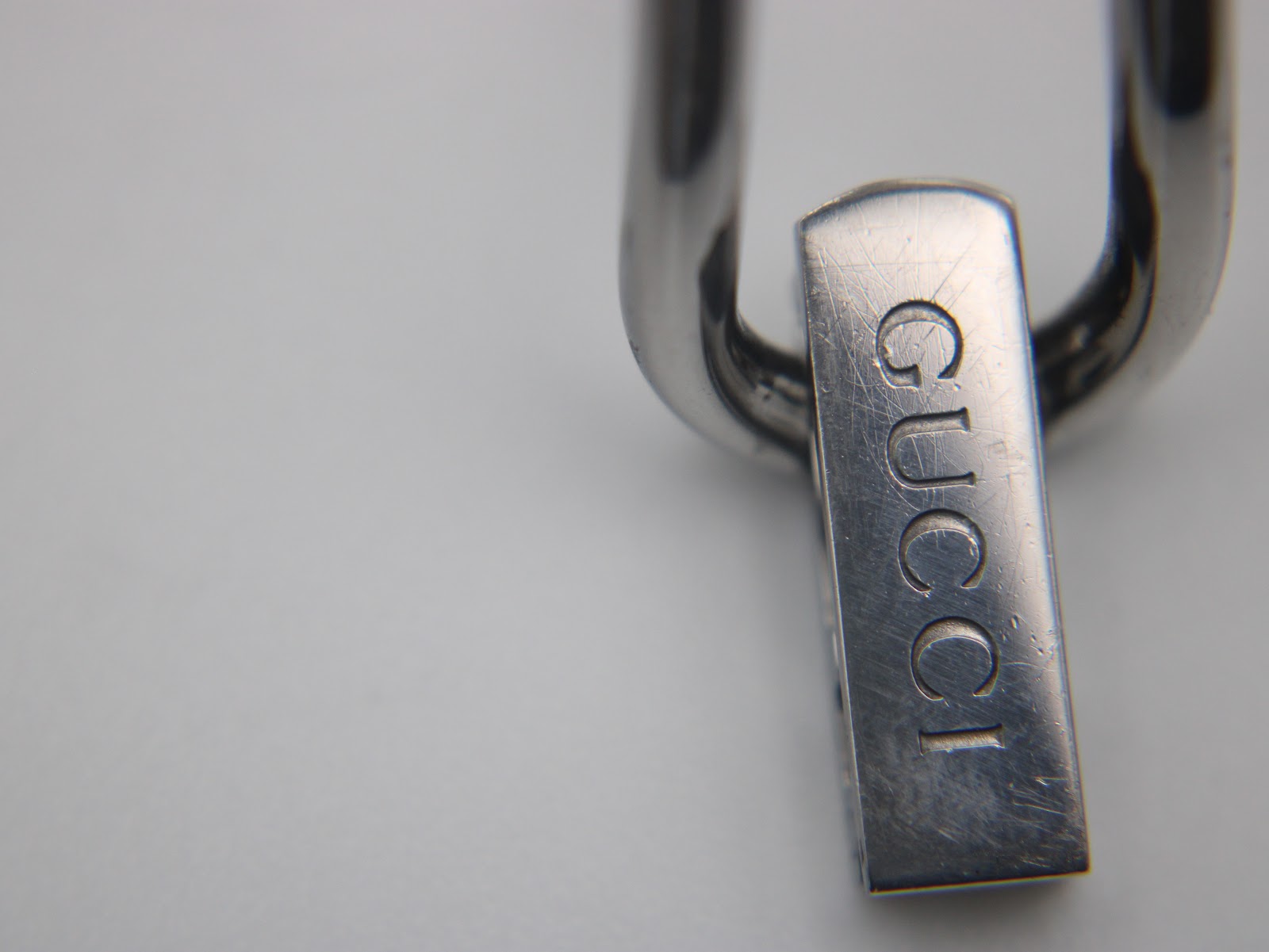 Extreme close-up of the integrated stainless steel bracelet's clasp, clearly showing the engraved "GUCCI" logo.