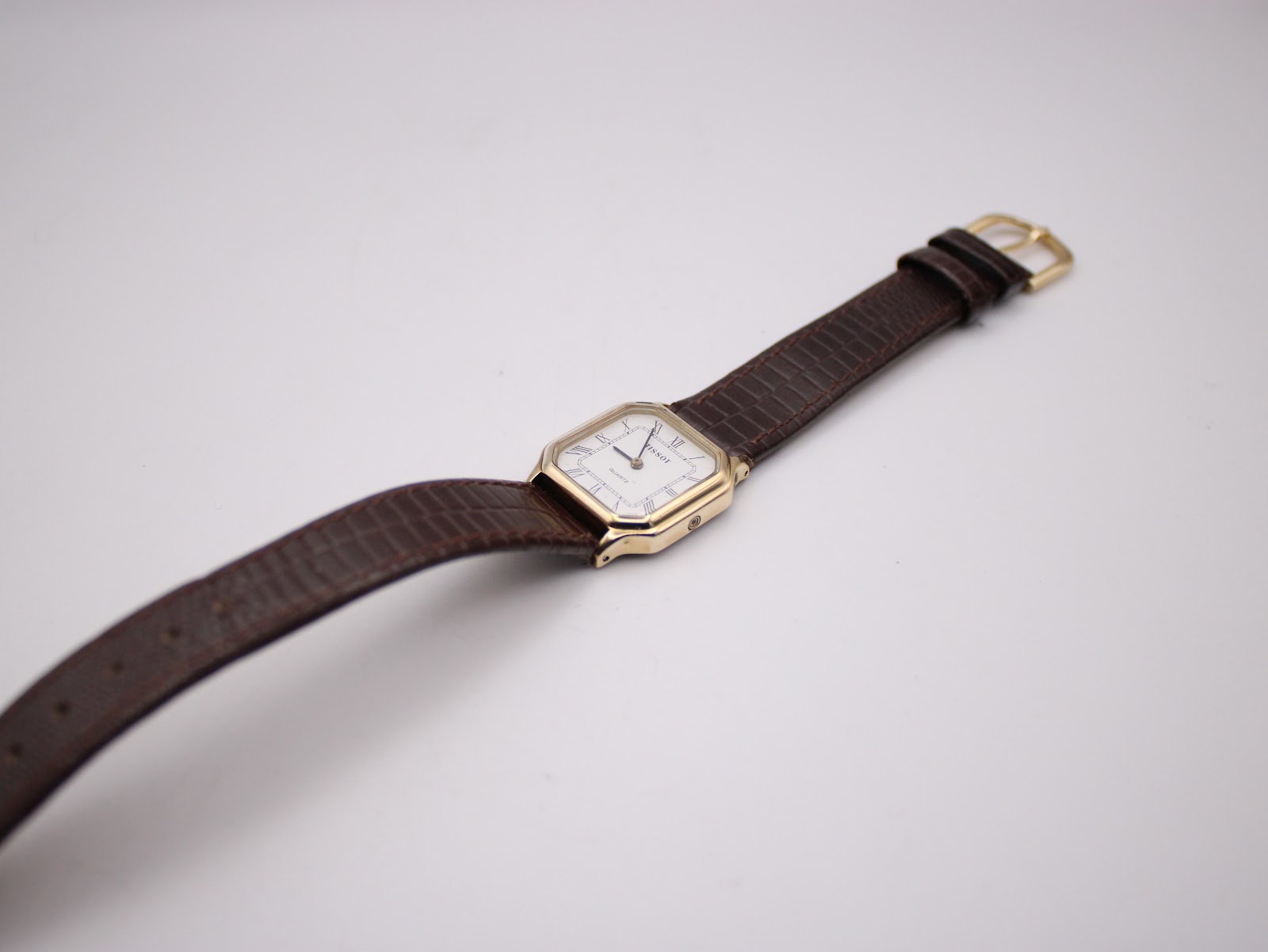 Overhead view of the Tissot 21589 watch with its brown crocodile-grain leather strap and gold-coloured buckle.