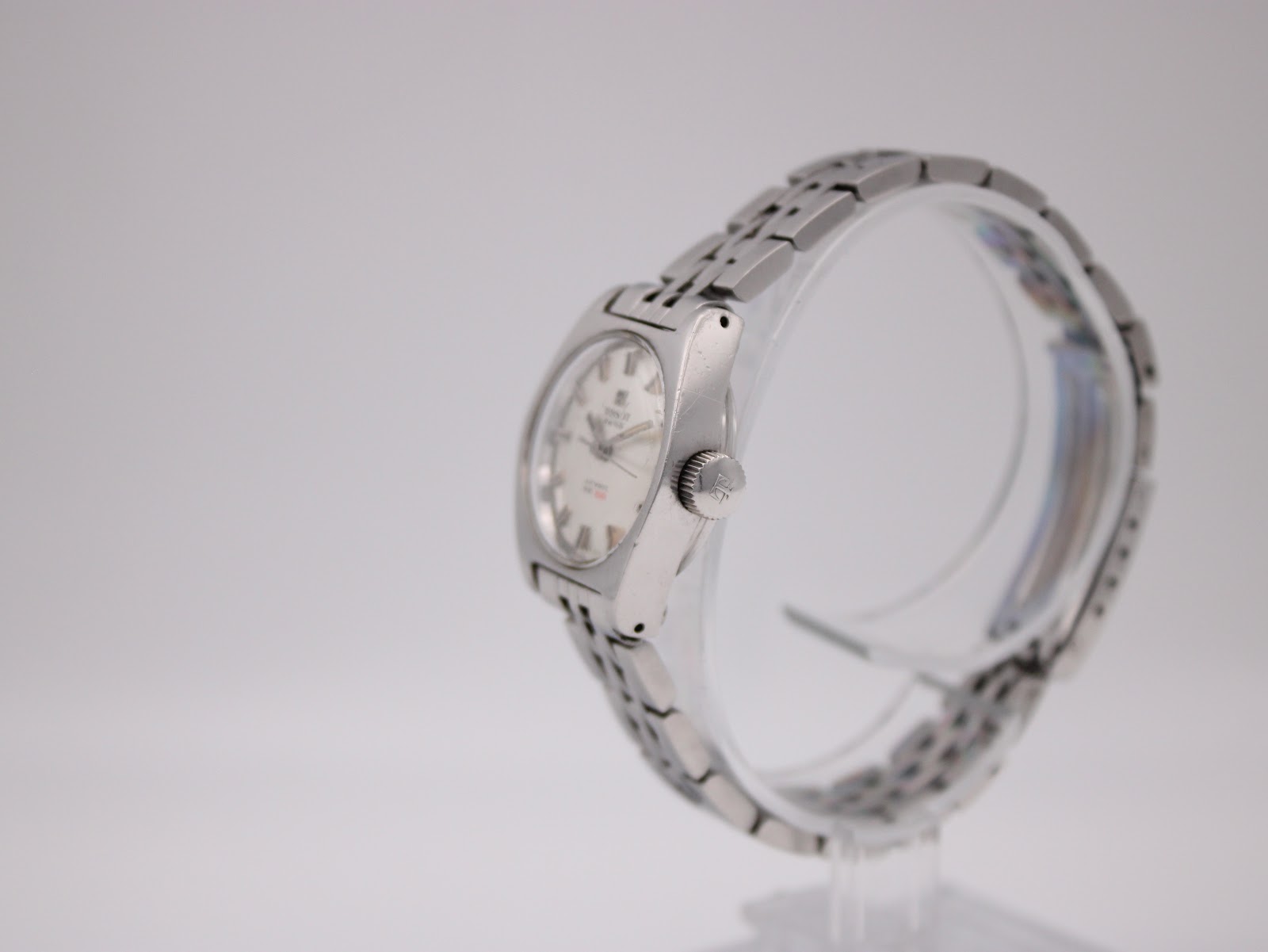 Angled side view of the Tissot PR 516 watch, showing the stainless steel tonneau case and bracelet links.