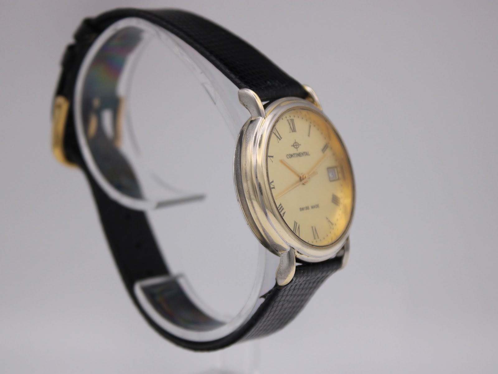 Angled side view of the Continental watch on a display stand, highlighting the polished two-tone case and the texture of the black leather strap.