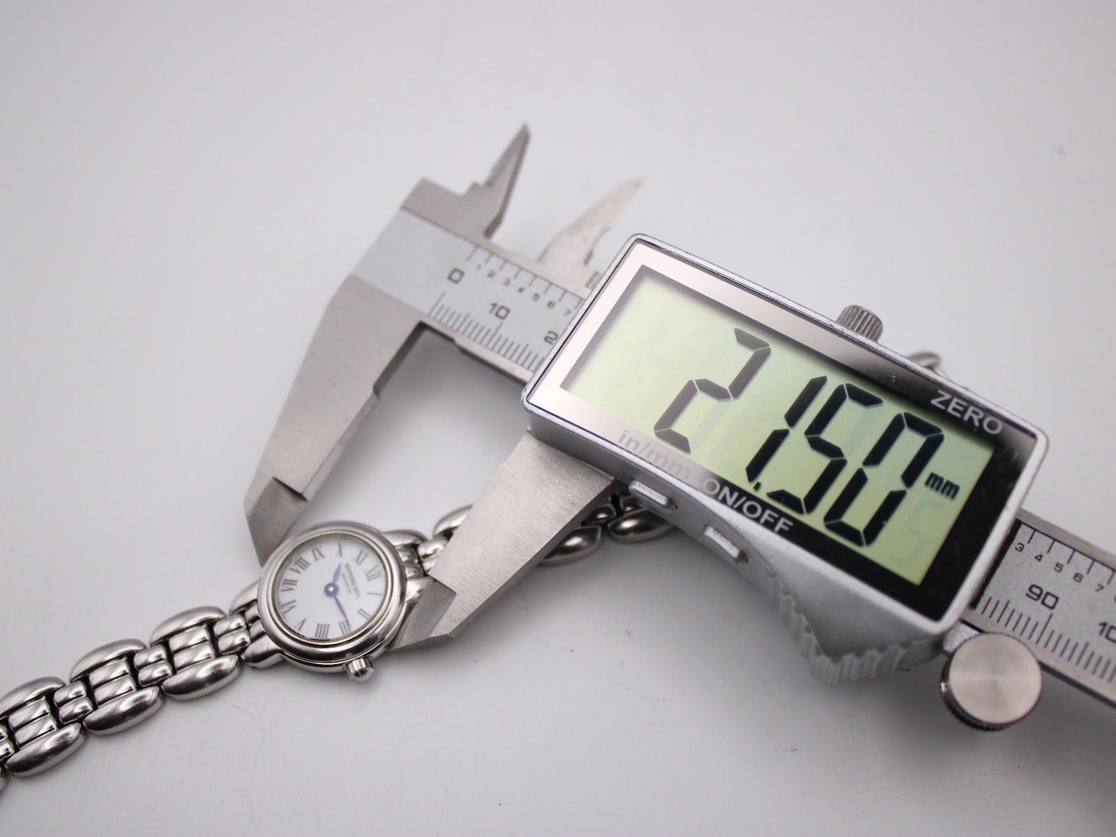 Top-down view of the Raymond Weil watch being measured by a digital caliper, displaying a case size of 21.50mm.