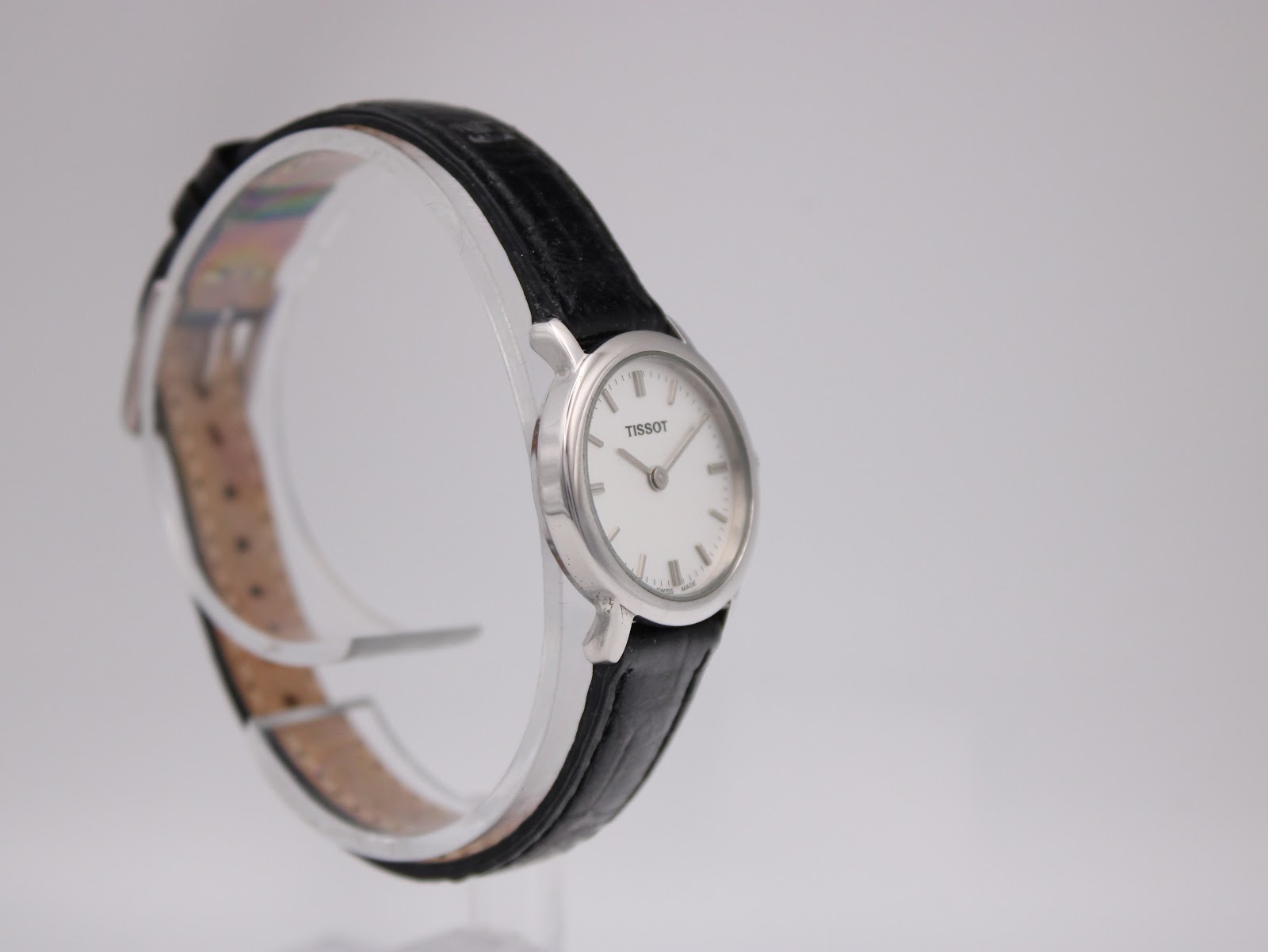 Opposite angled side view of the Tissot C226K watch on a transparent display stand, highlighting the case and strap.