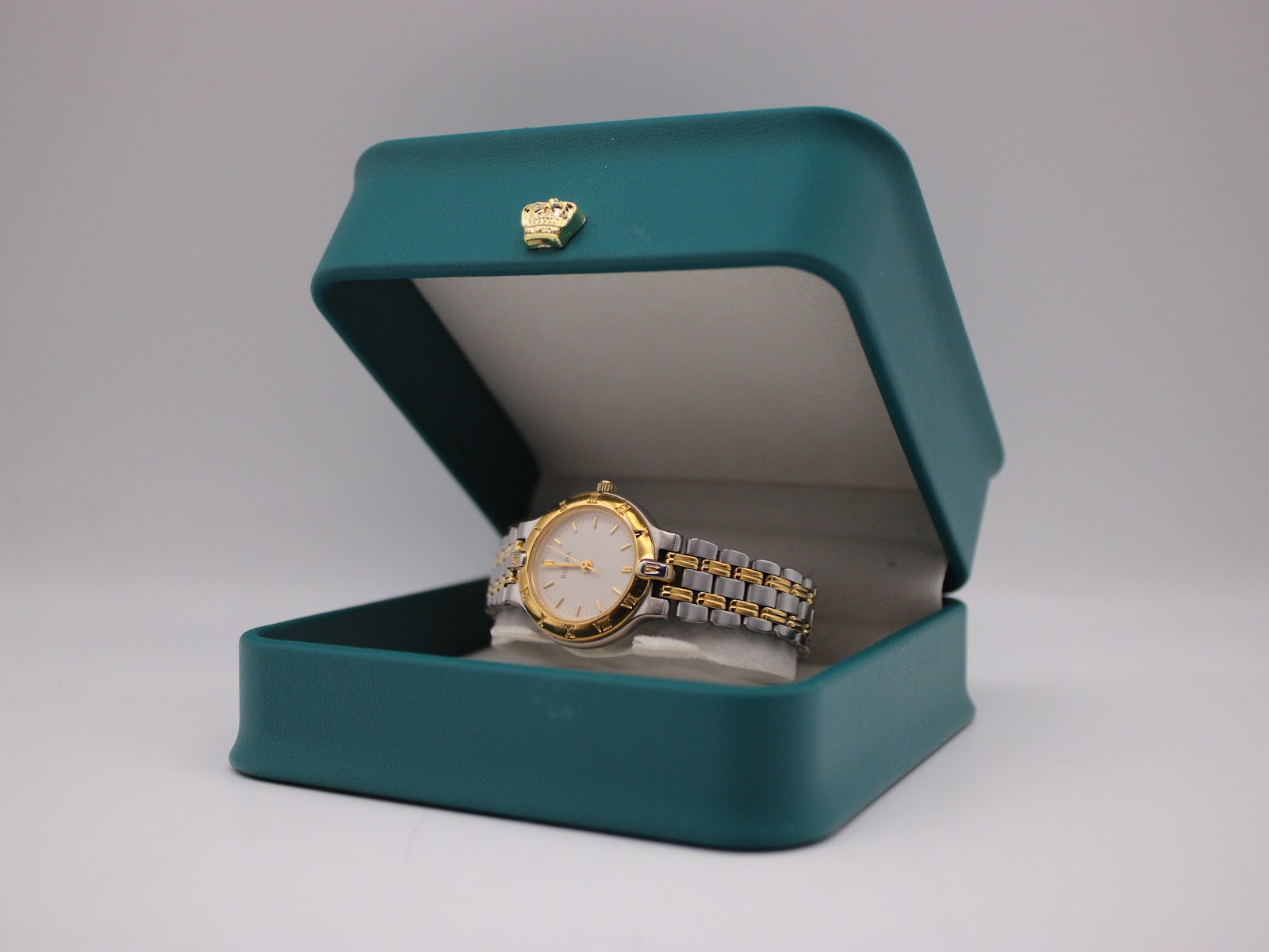 The Bulova watch resting inside an open green presentation box with a gold crown emblem.