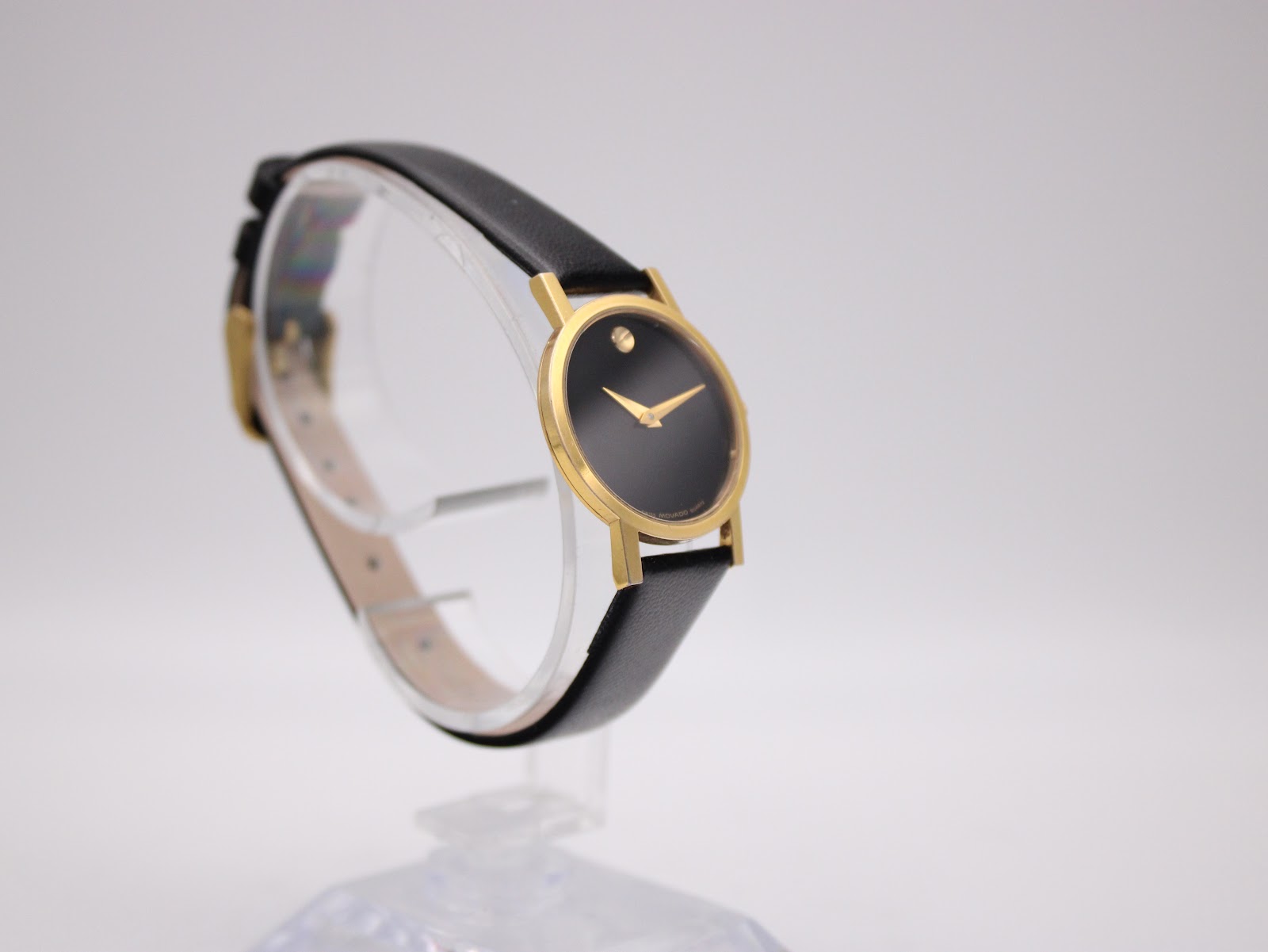 Another angled view of the watch, highlighting its slim profile and the simple gold-tone buckle on the black strap.