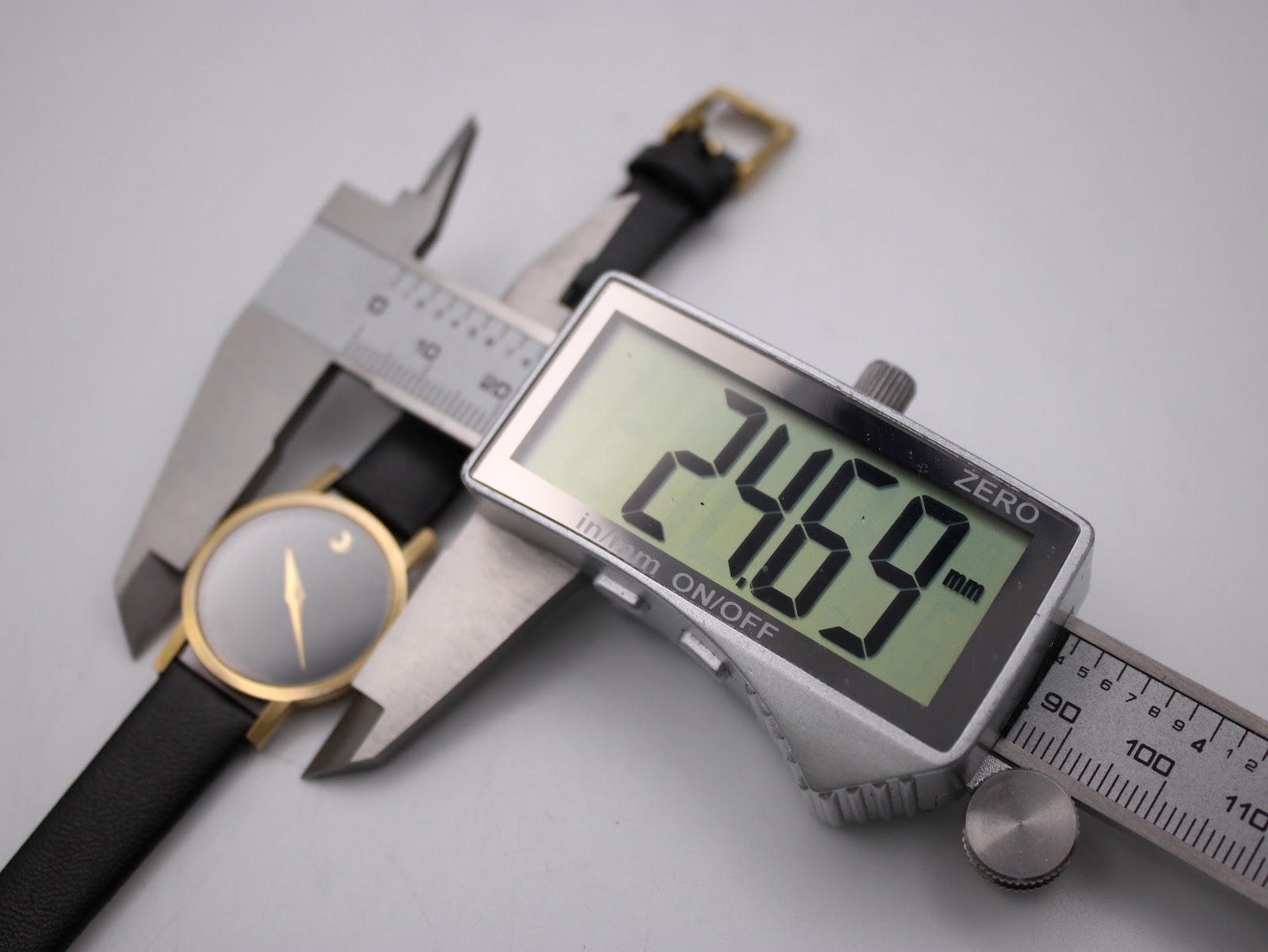 Digital caliper measuring the watch case diameter, displaying an exact measurement of 24.69mm.