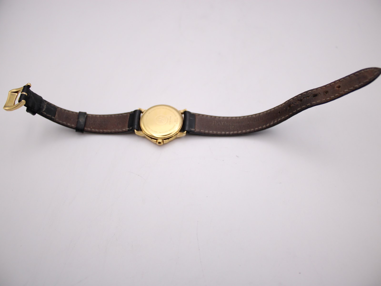 Overhead view of the Raymond Weil 9972 watch with its black leather strap laid flat, showing the case back and the underside of the strap.