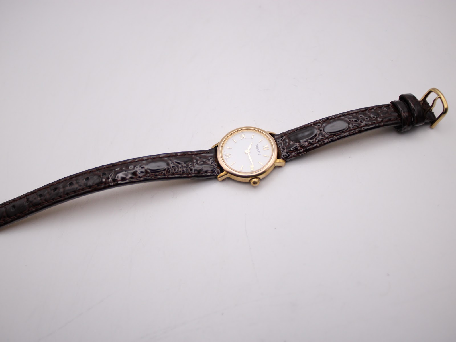 Overhead view of the Tissot C225K watch with the brown leather strap laid flat on a white surface.