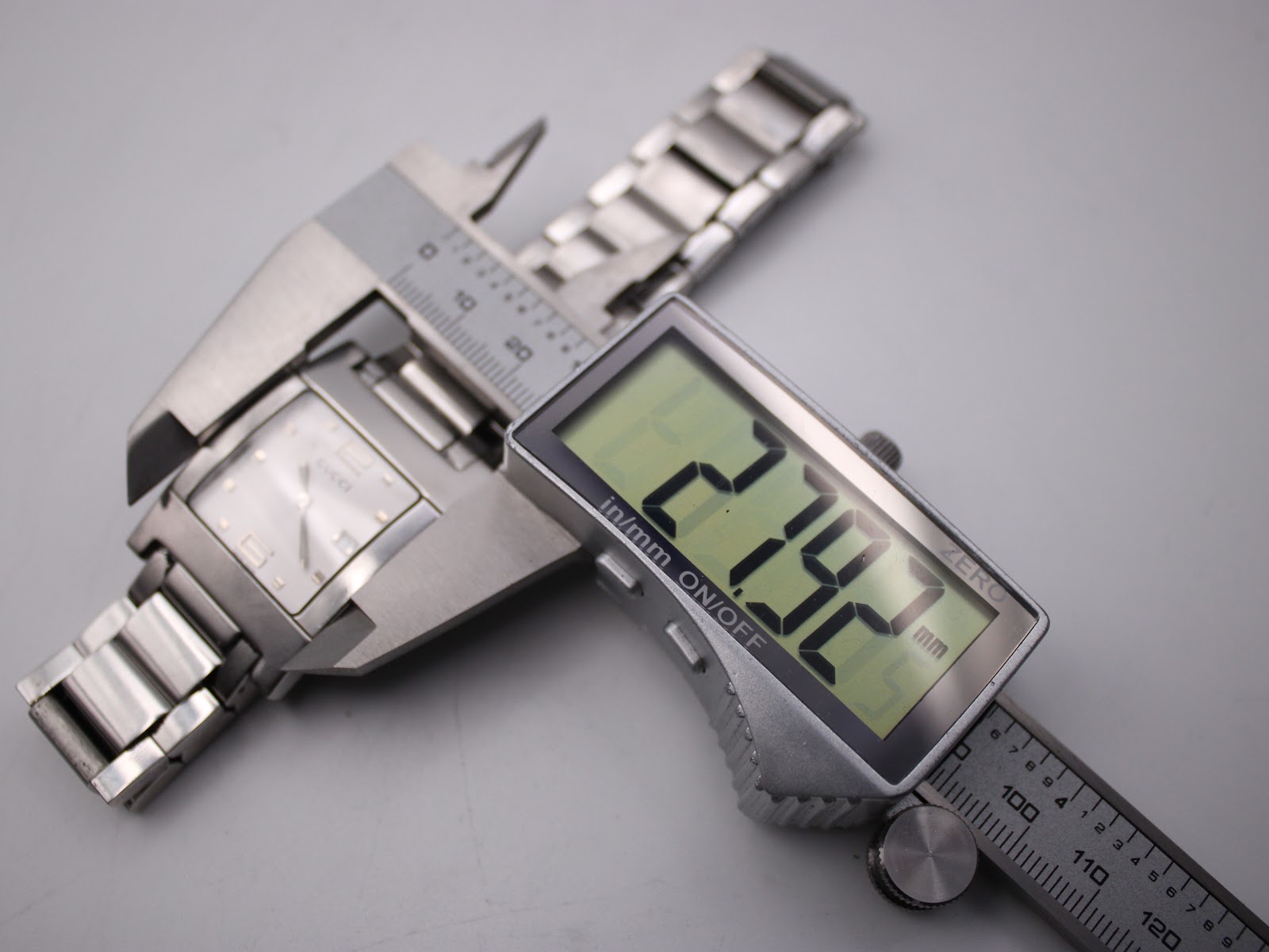 Digital caliper measuring the case width of the Gucci 7700 M watch, displaying an exact measurement of 27.92mm.