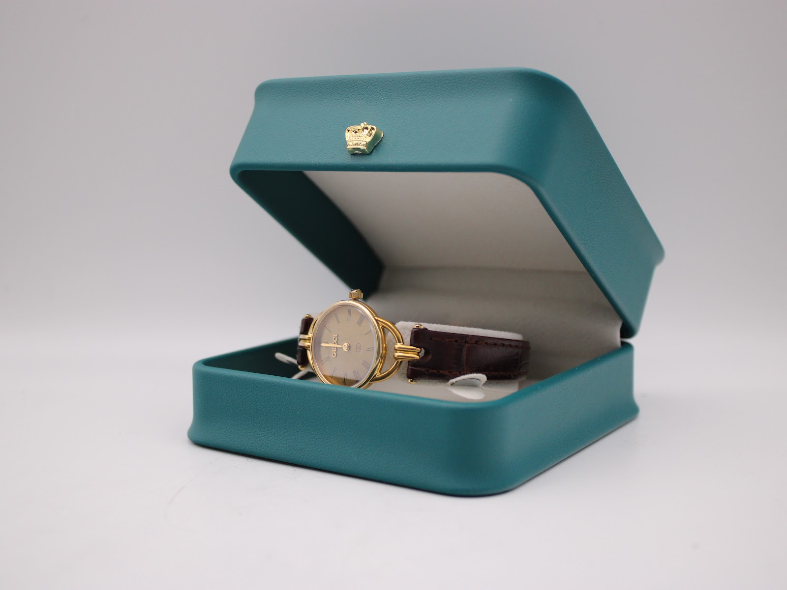 The Gucci 6000L watch resting inside a teal presentation box.