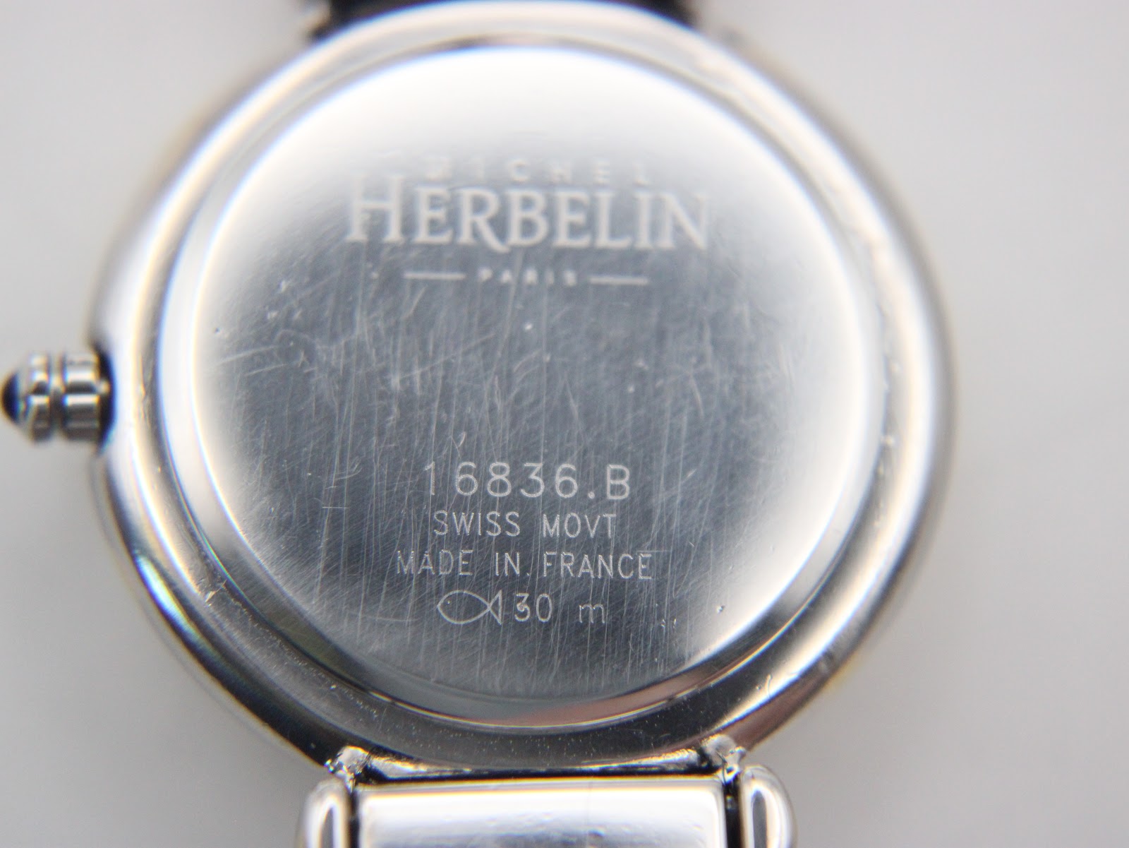 Close-up of the Michel Herbelin watch case back showing model 16836.B, 'Swiss Movt', 'Made in France', and '30 m' water resistance.