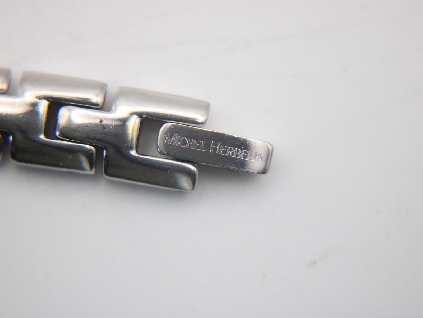 Close-up of the watch clasp, engraved with "MICHEL HERBELIN".