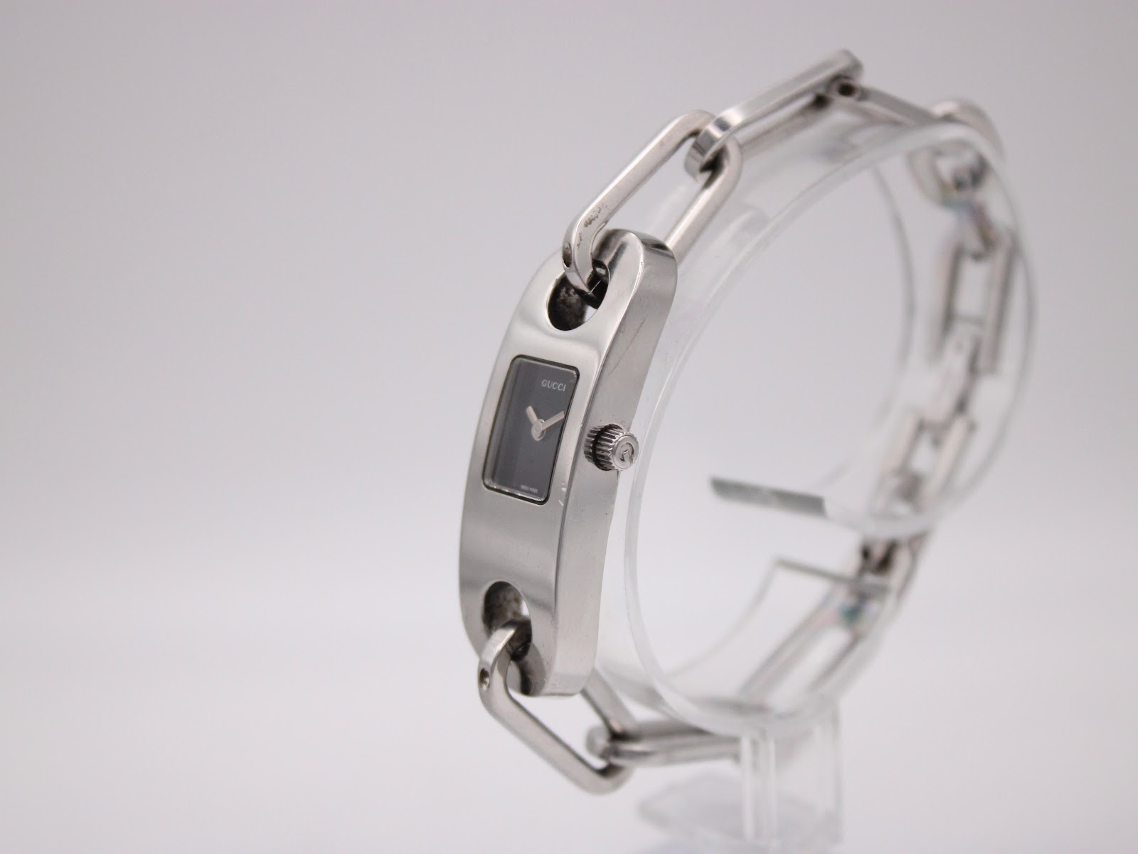 Angled side view of the Gucci 6100L watch, highlighting the profile of the case and the polished finish of the stainless steel.