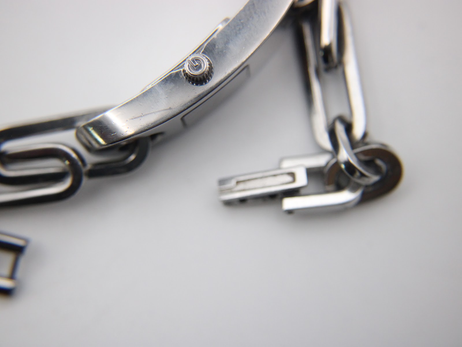 Detail shot of the watch crown and the integrated bracelet clasp mechanism, revealing some minor wear.
