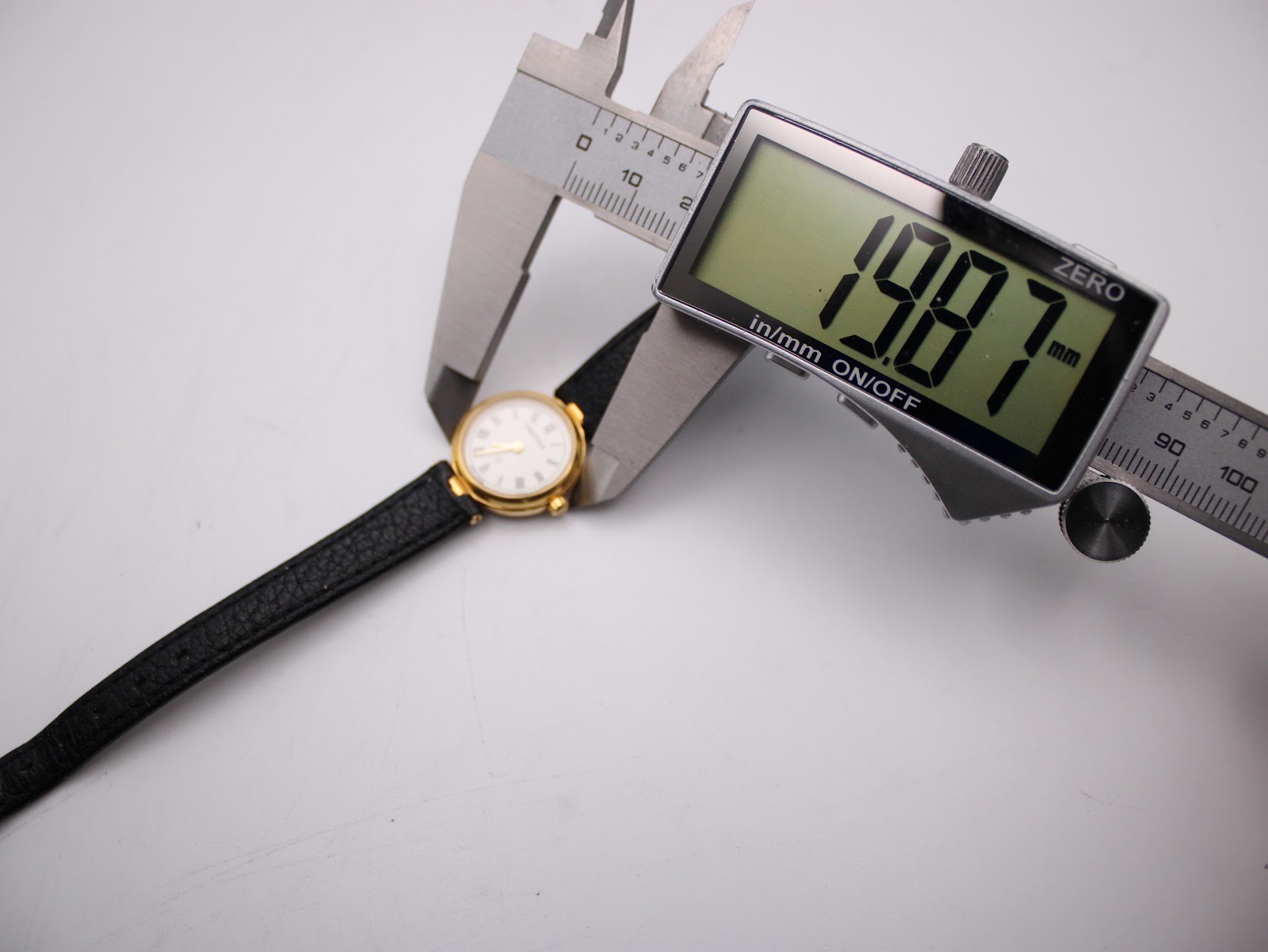Digital caliper measuring the watch case diameter at 19.87mm.