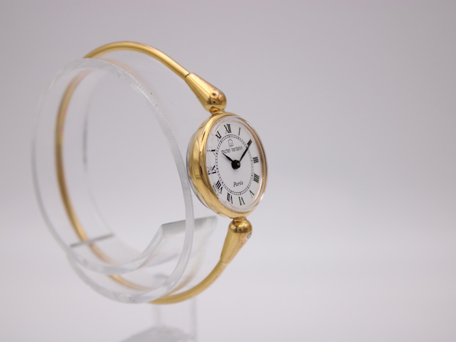 Angled side view of the Michel Herbelin ladies' watch, highlighting its gold tone case and integrated bangle design.