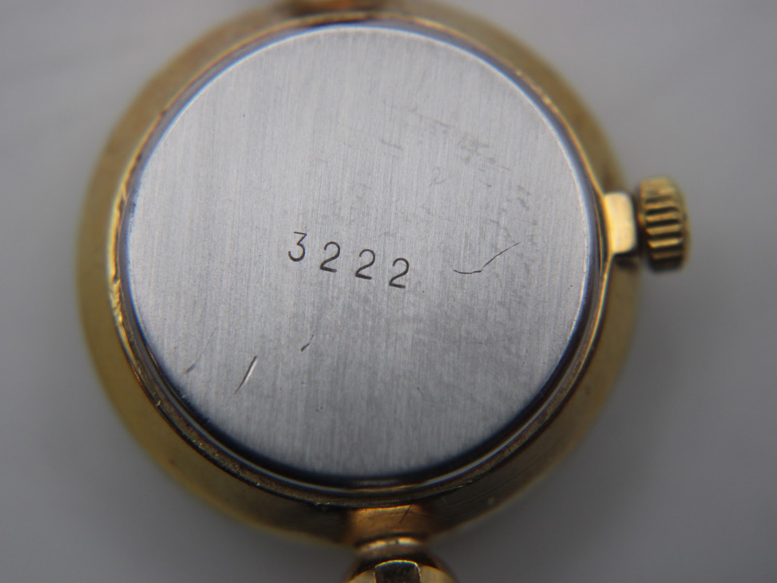 Close-up of the watch's case back, revealing the serial number '3222' engraved on the brushed steel centre.