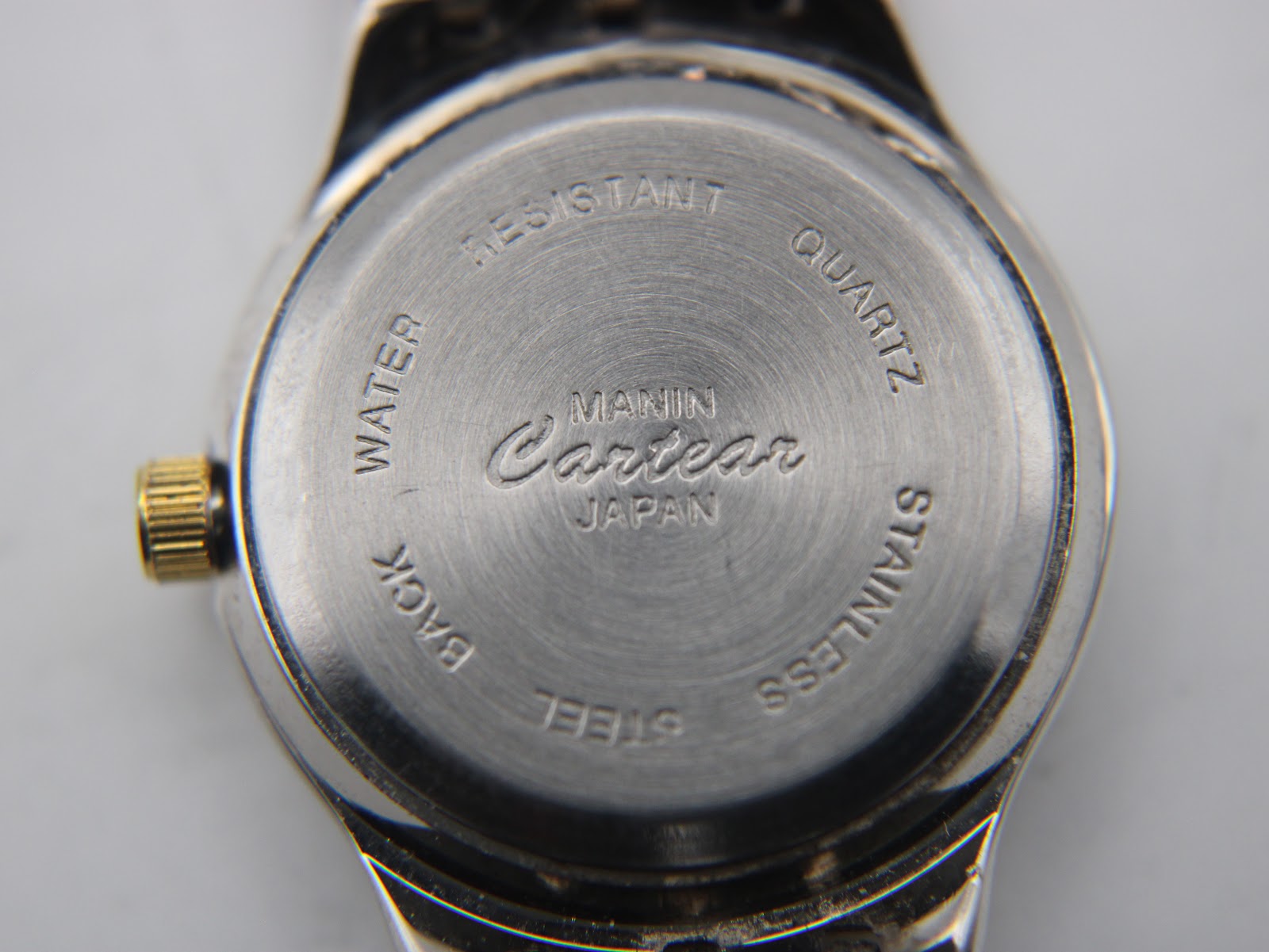 Close-up of the watch case back, showing 'Manin Cartear Japan' and 'Water Resistant Stainless Steel Back Quartz' engravings.
