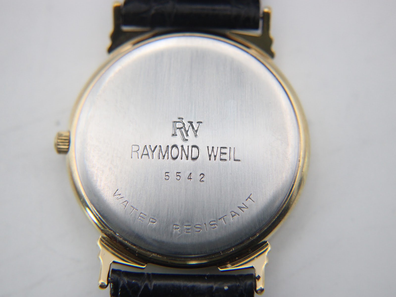 Close-up of the watch's stainless steel case back with "RW Raymond Weil 5542 WATER RESISTANT" engraving.