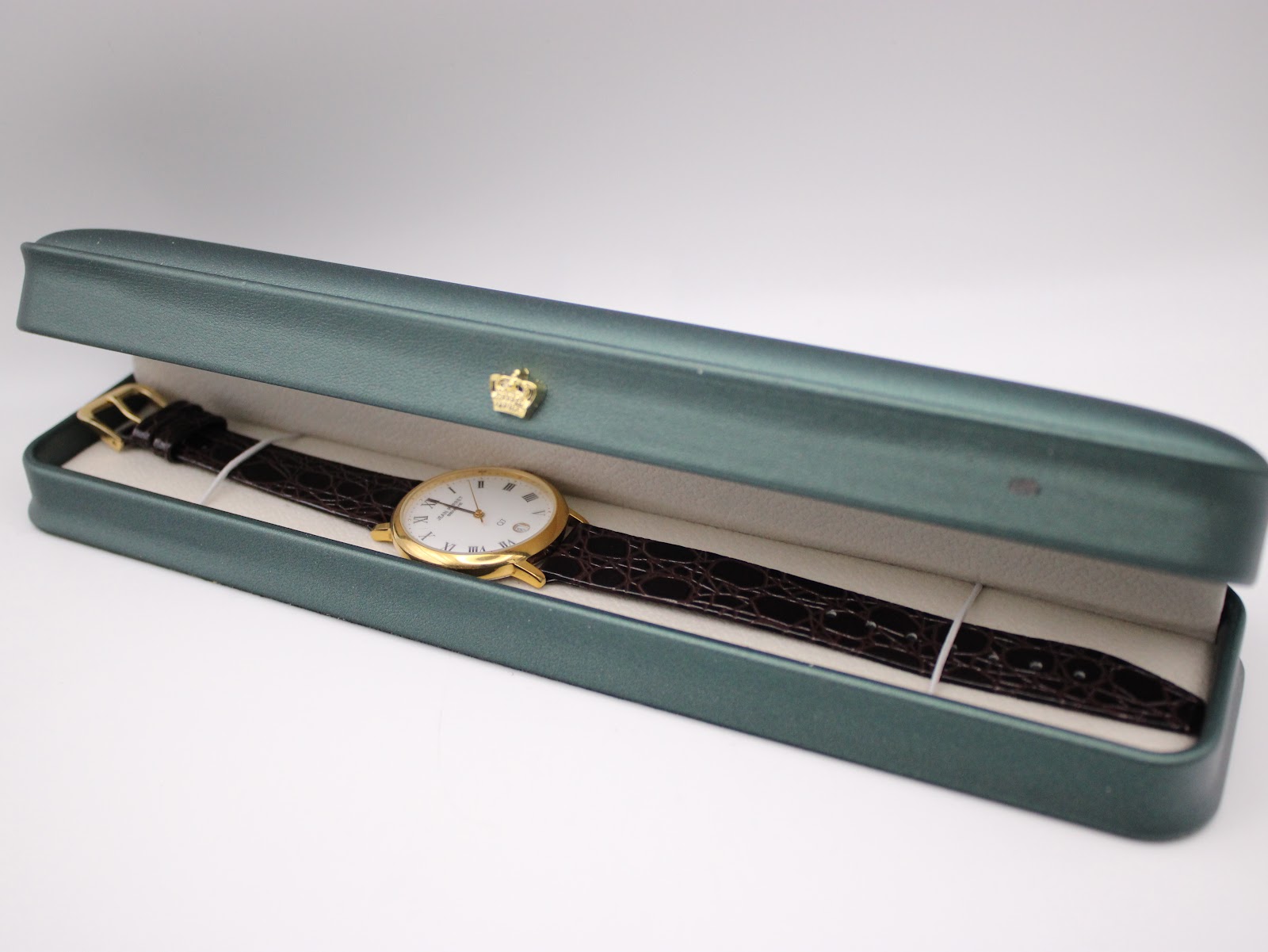 The Jean Perret QJ watch laid inside a generic dark green watch box.