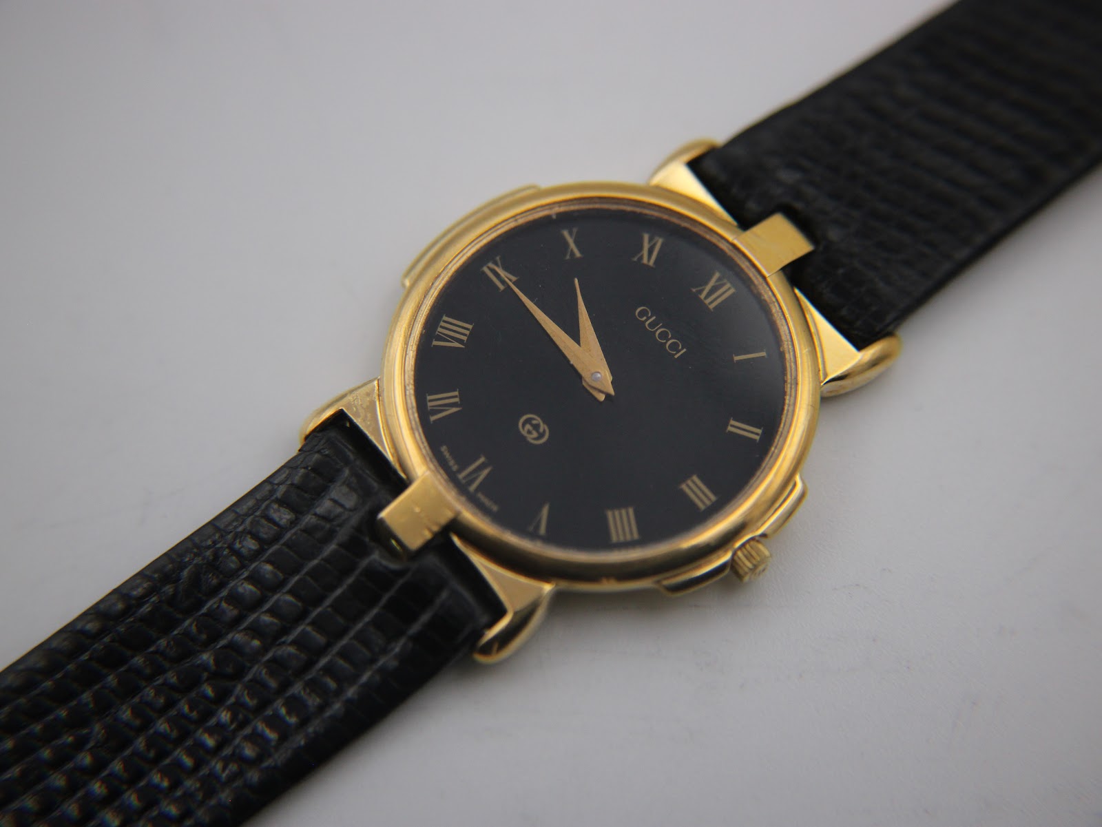 Slightly overhead angled view of the Gucci 3400M watch face and the black leather strap, showcasing the dial's details.