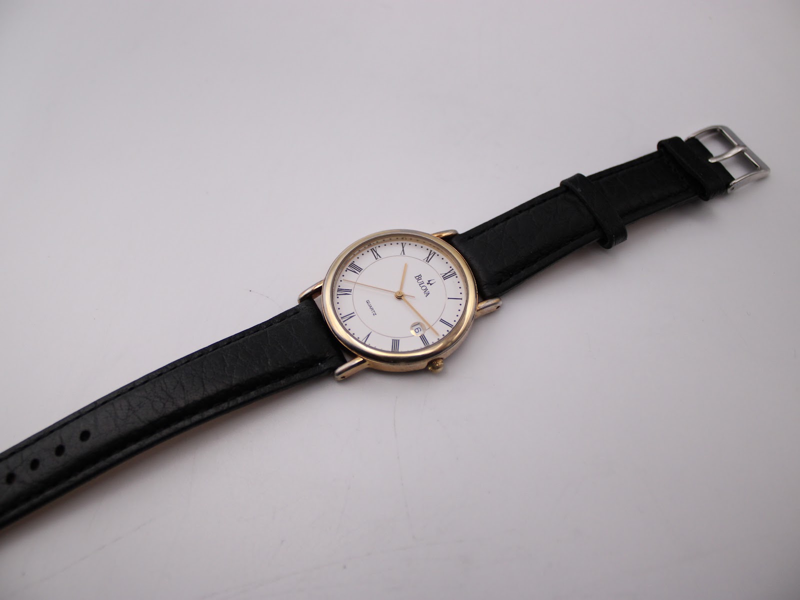 Full length top view of the Bulova watch with its black leather strap laid flat.