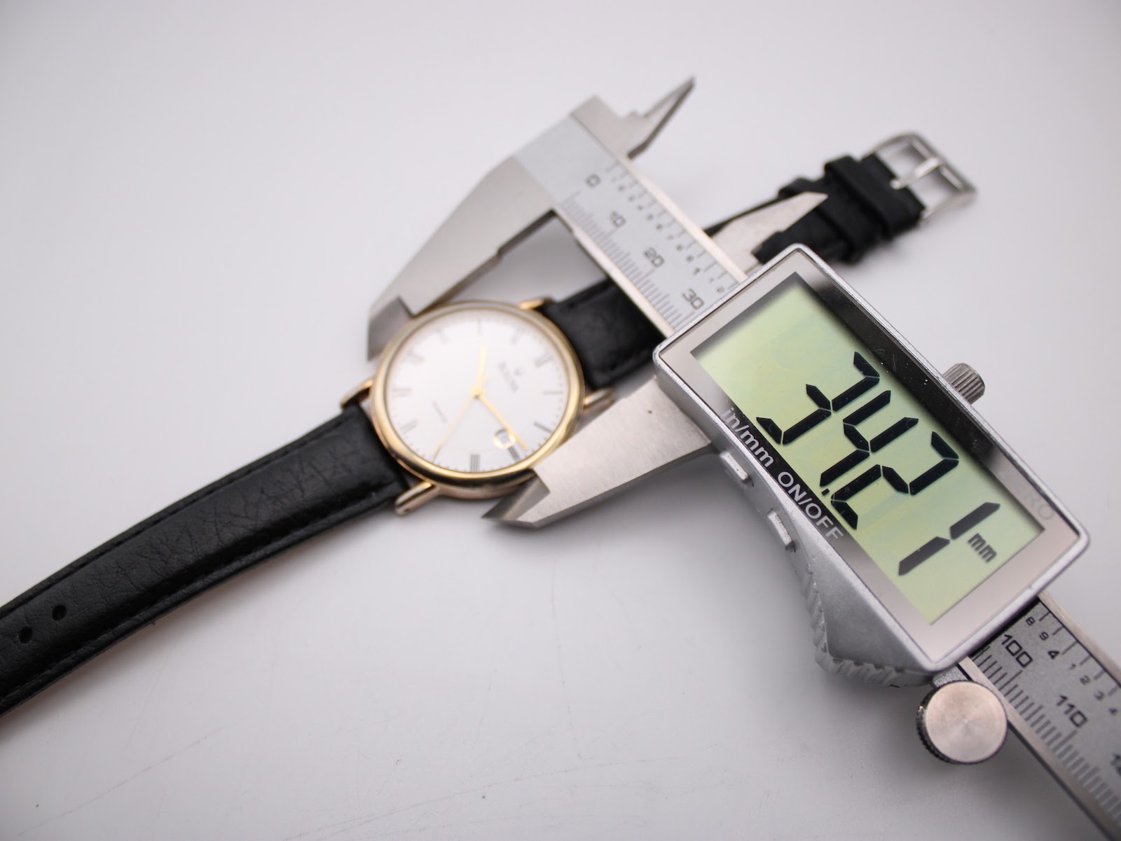 Digital caliper measuring the Bulova watch case diameter at 34.2mm.