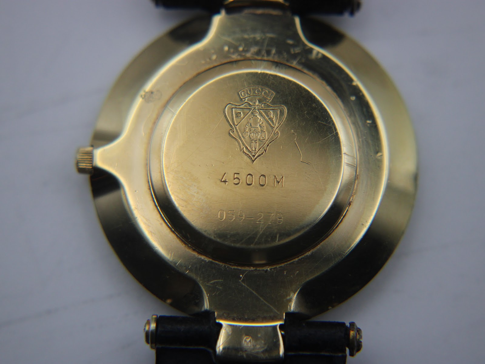 Close-up of the gold-tone case back of the Gucci 4500 M, showing the engraved Gucci crest, model '4500 M' and serial '059-279'.