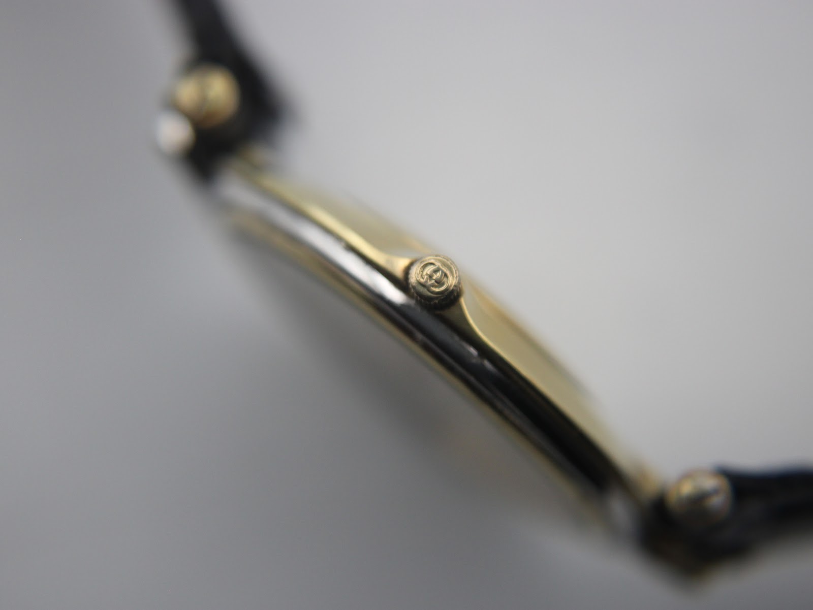 Close-up side view of the Gucci 4500 M crown, showing the embossed Gucci 'G' logo.