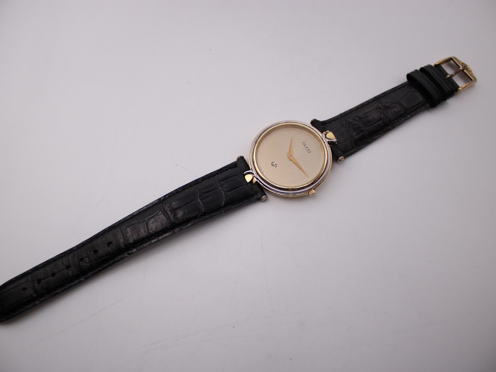 Overhead view of the entire Gucci 4500 M watch, displaying the black crocodile-effect leather strap laid flat.