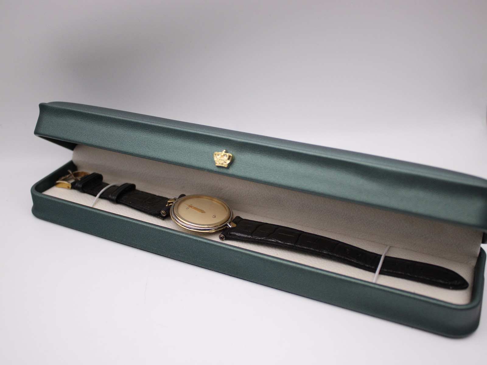 The Gucci 4500 M watch placed in a green presentation box, with the black leather strap visible.