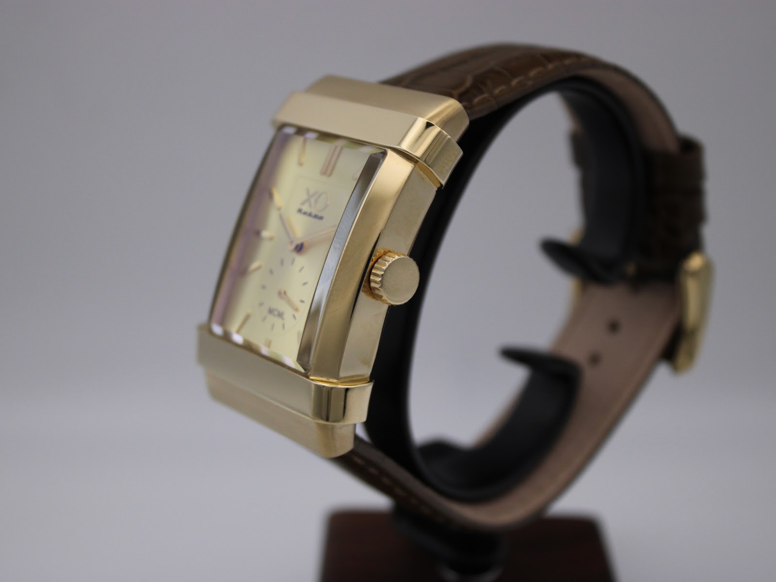 Angled side view of the XO RETRO watch on a stand, highlighting the rectangular gold-tone case and crown, with the brown crocodile-effect leather strap.