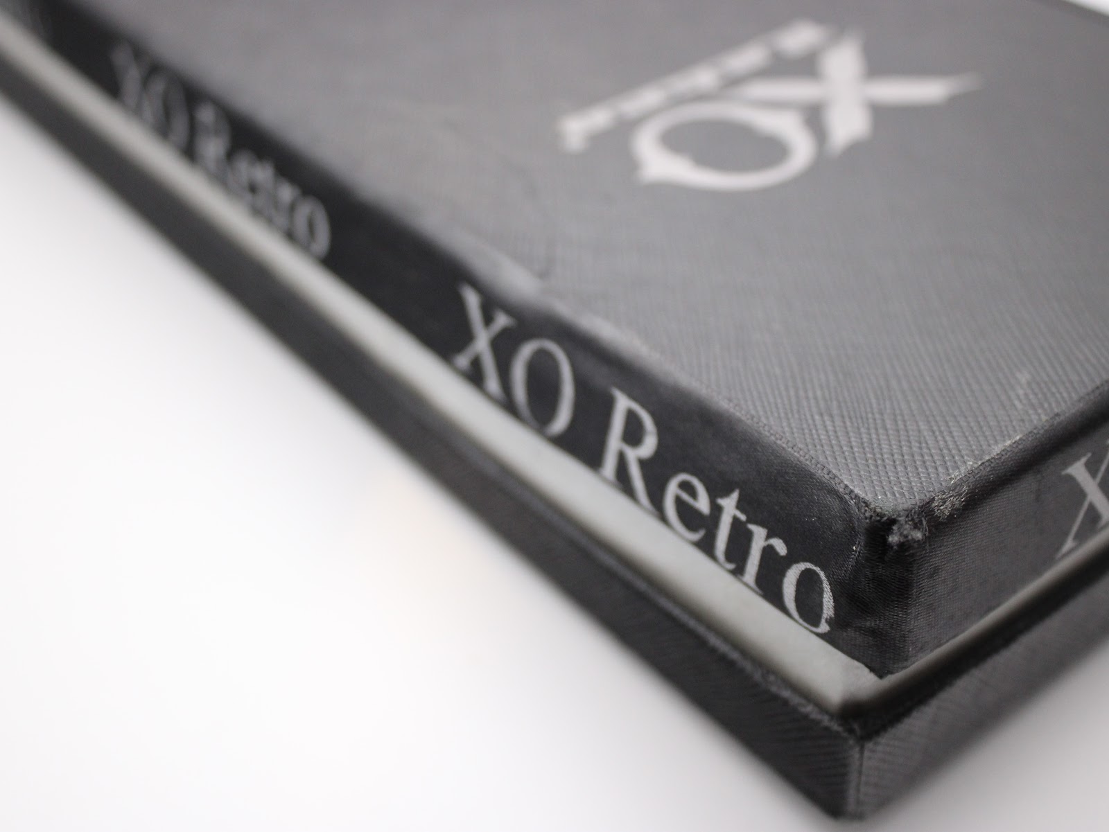 Side view of the black XO RETRO presentation box, highlighting its texture and the repeated brand name along the edge.