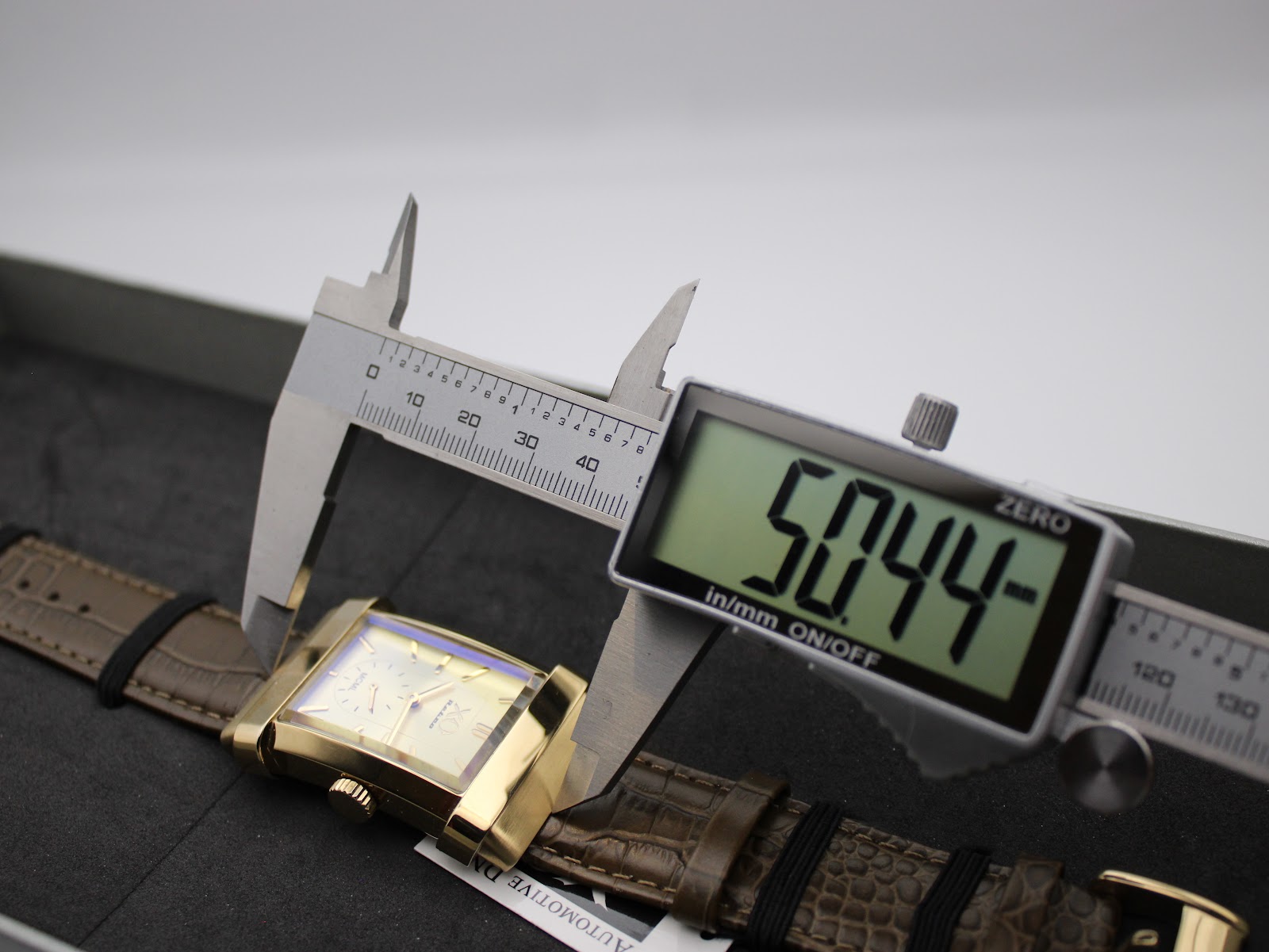 Digital caliper measuring the length (lug-to-lug) of the XO RETRO watch case at 50.44mm, showing the watch inside its box.